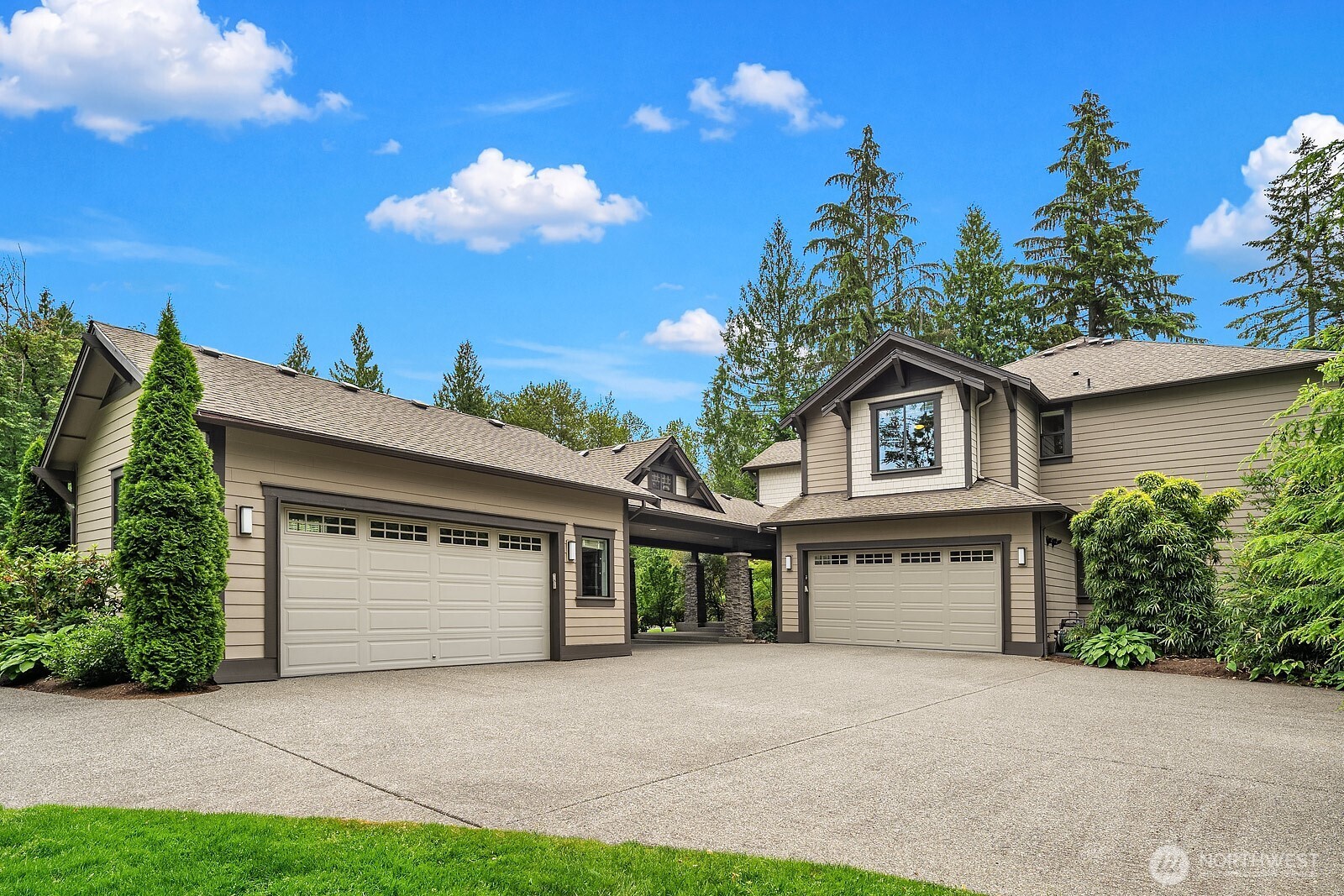 The impressive 4-car garage and sweeping wrap-around driveway provide exceptional parking and storage, all framed by mature evergreens that enhance the home's private and grand street presence.