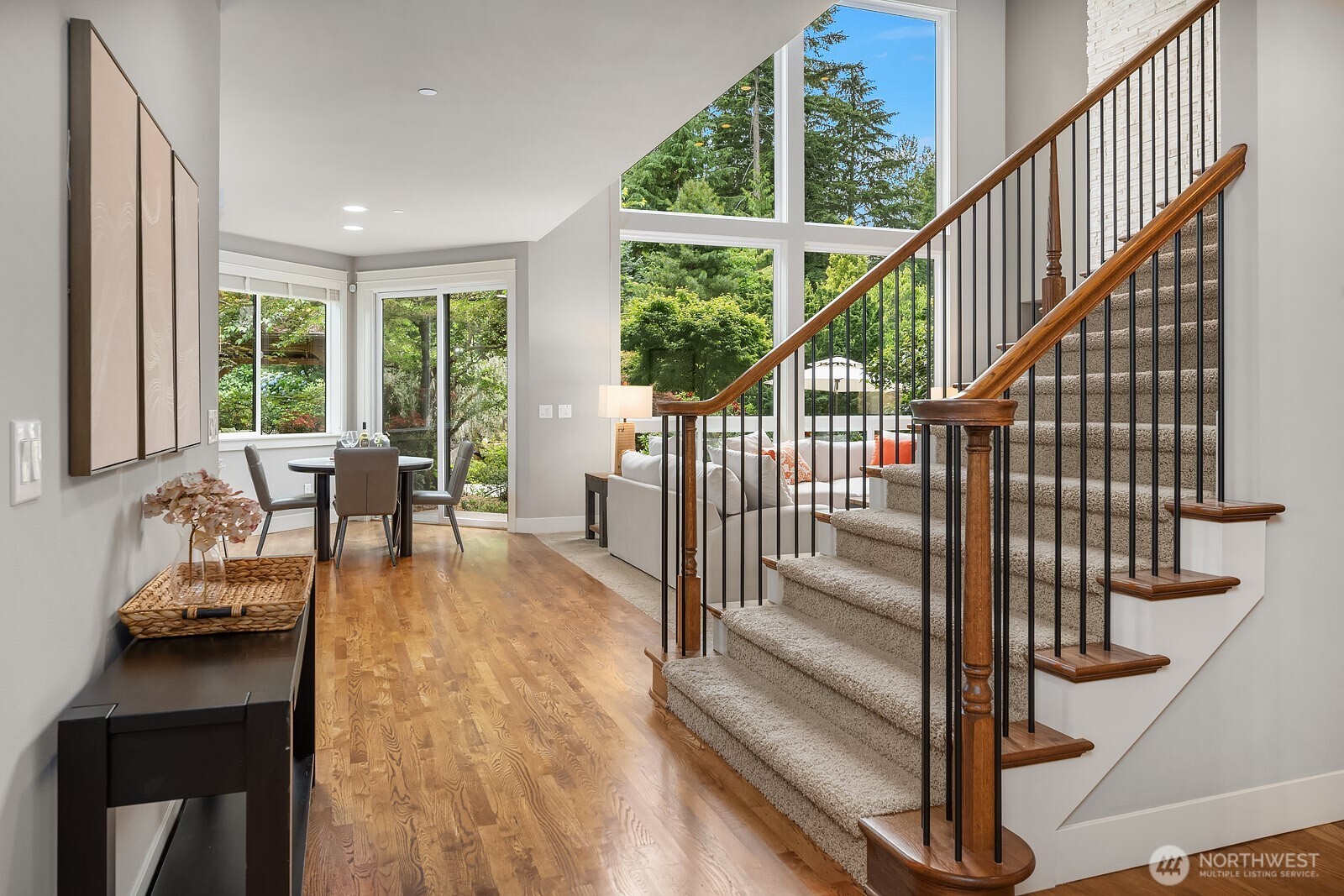 A beautifully crafted staircase with sleek metal balusters anchors this light-filled space, where hardwood floors and oversized windows invite the outdoors in. The open, airy feel continues the home's seamless blend of refined details and natural warmth.