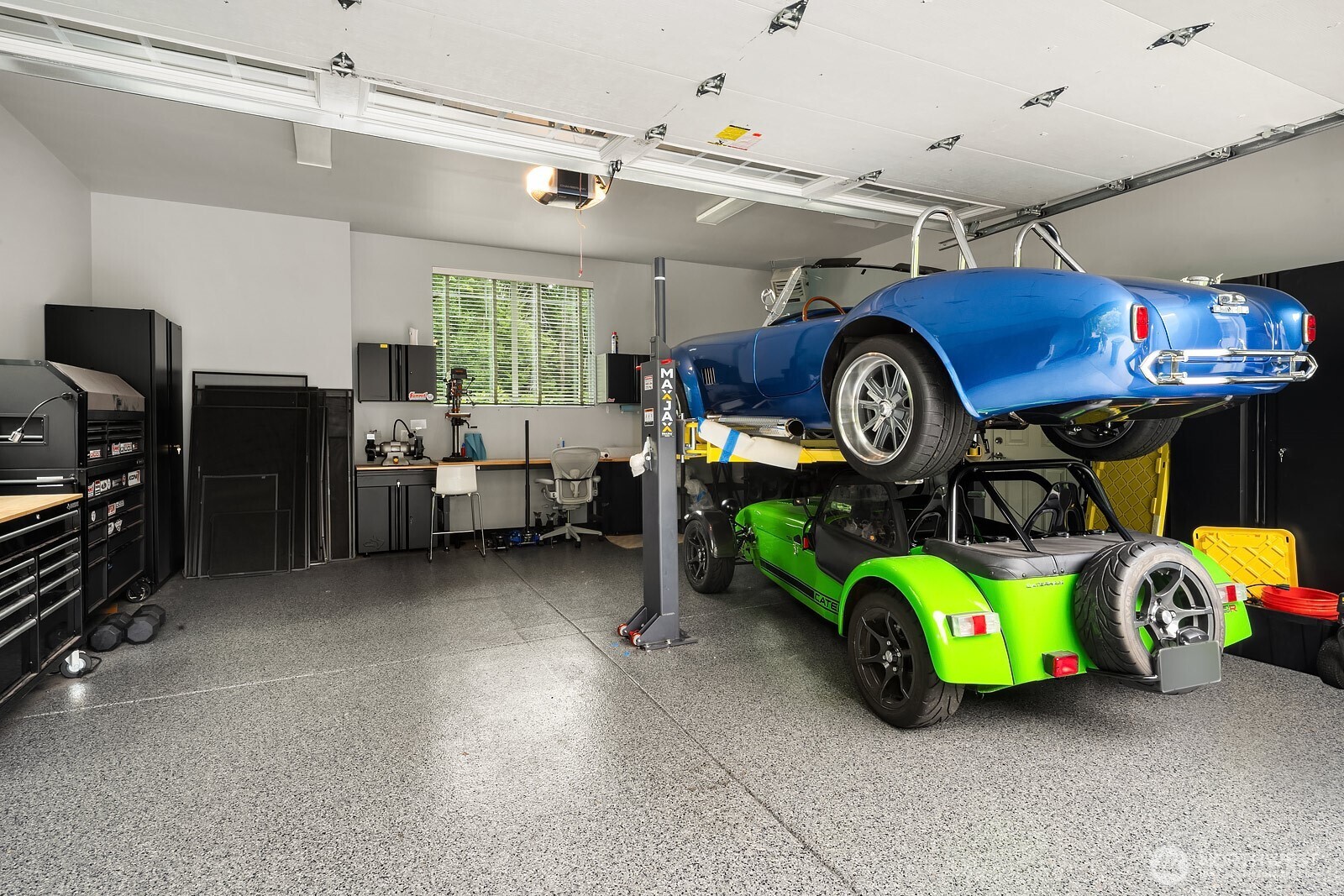 The expansive garage interior offers exceptional space and functionality, featuring a vehicle lift, epoxy flooring, and custom storage solutions that are a dream for car enthusiasts and hobbyists alike.