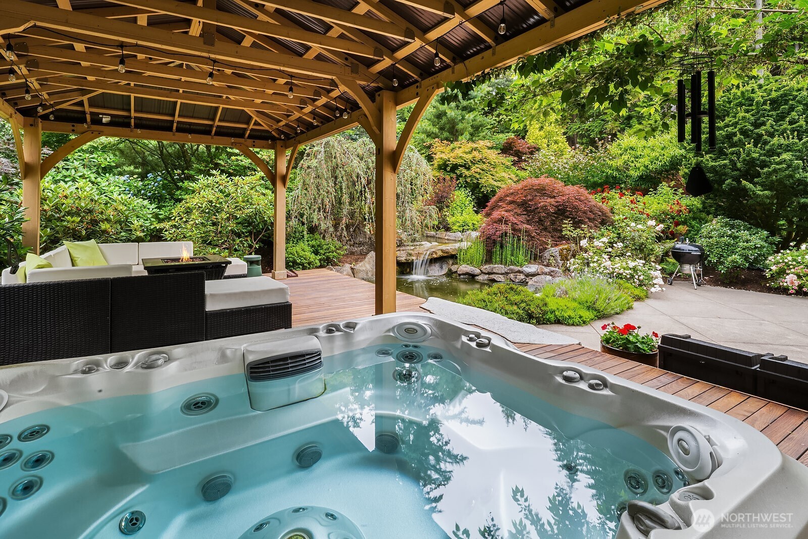 The covered hot tub offers a private and luxurious retreat, tucked beneath a beautiful pergola and surrounded by lush, mature landscaping that creates a truly resort-like atmosphere right in your own backyard.
