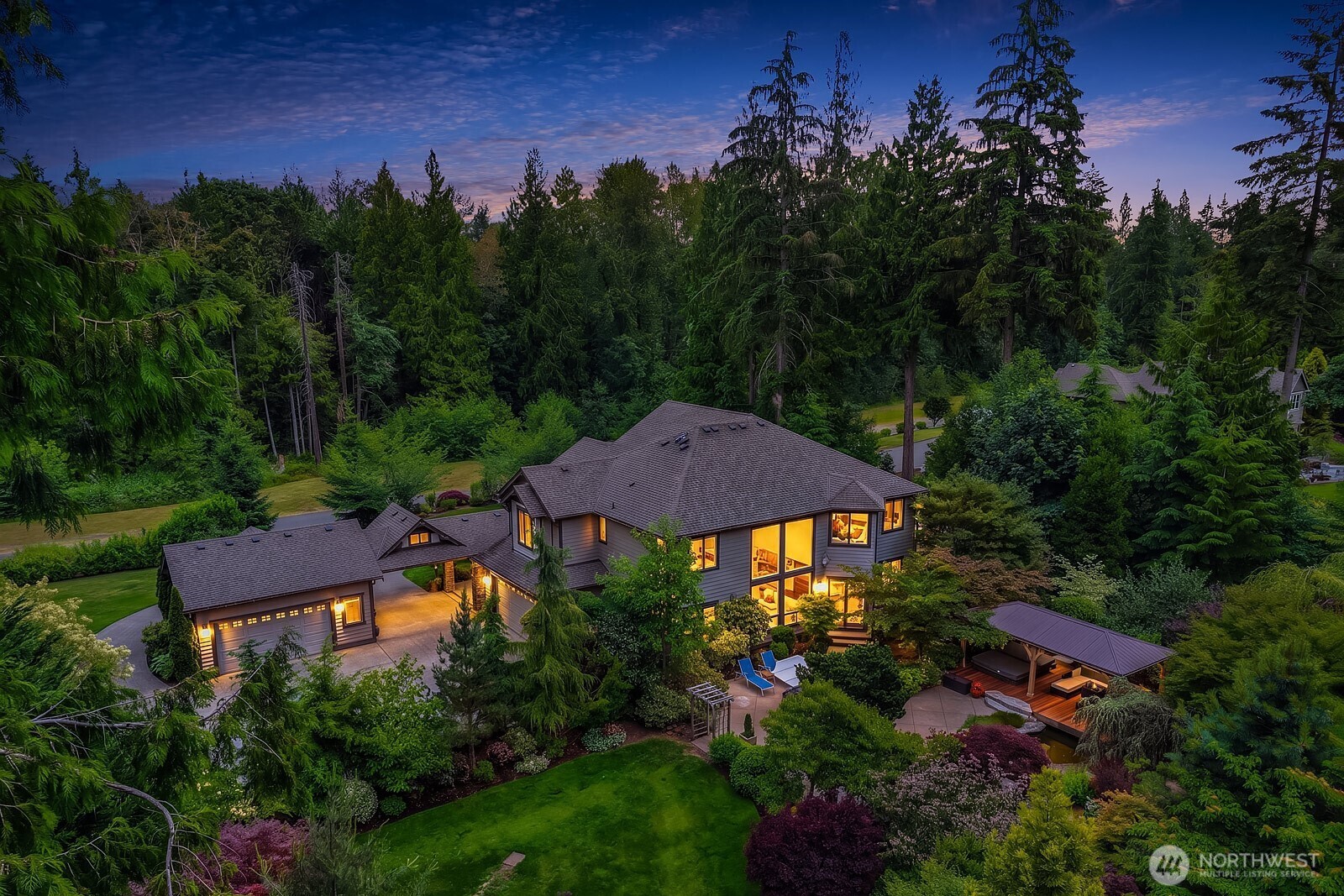 A breathtaking aerial dusk view captures the full grandeur of this exceptional estate, showcasing the beautifully illuminated home, sweeping grounds, and the incredible privacy afforded by the surrounding mature trees and nearly 2.5 acres of lush Pacific Northwest landscape.