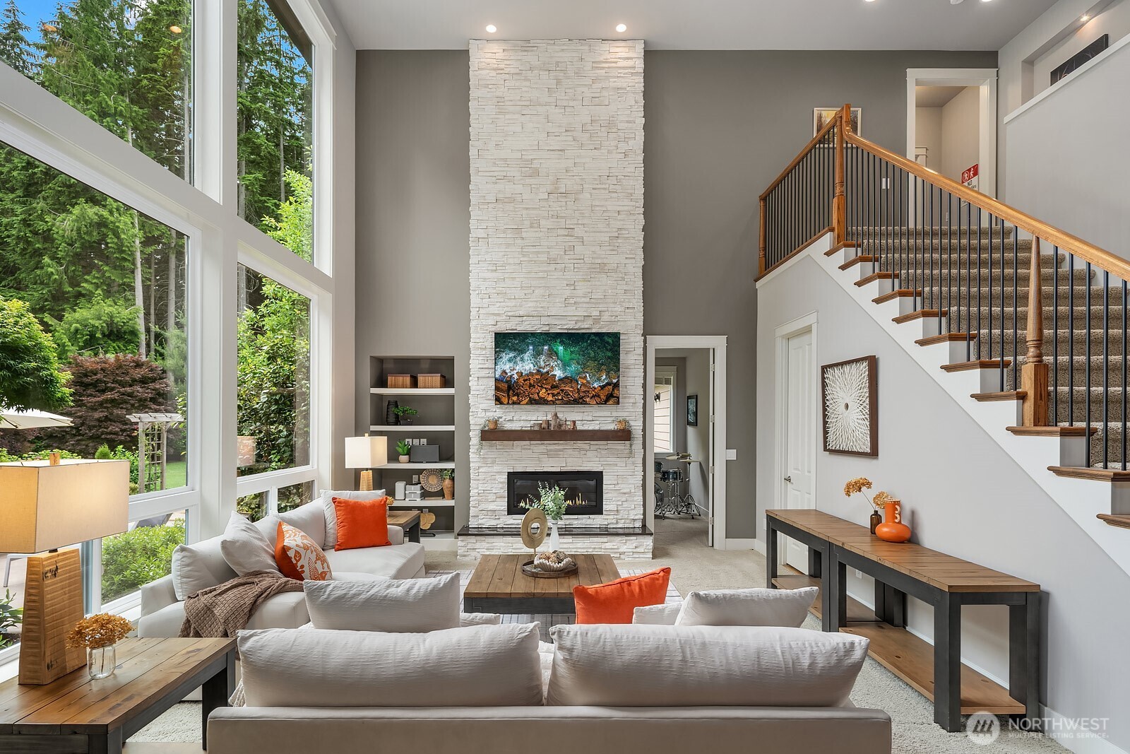 Soaring two-story ceilings and a wall of windows flood this expansive living room with natural light, while a sleek fireplace serves as the room's elegant focal point. Thoughtful built-ins and an open-concept layout make this space as functional as it is impressive.
