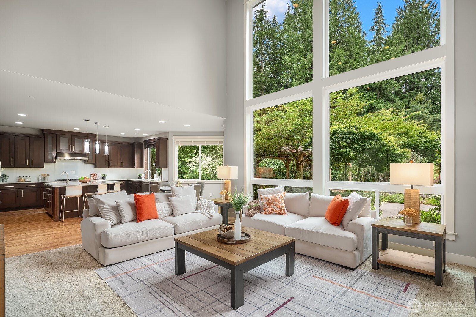 Floor-to-ceiling windows frame a breathtaking backdrop of mature Pacific Northwest trees, bringing the beauty of the nearly 2.5-acre property into every corner of this serene living space. The open sightlines to the chef's kitchen make this an ideal setting for both relaxed everyday living and effortless entertaining.
