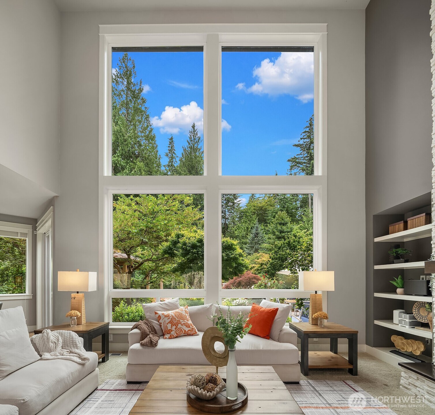 A second angle of this stunning great room showcases the seamless connection between the living area and the gourmet kitchen beyond, all bathed in natural light from the soaring window wall. The lush wooded views and thoughtful layout make this the true heart of the home.