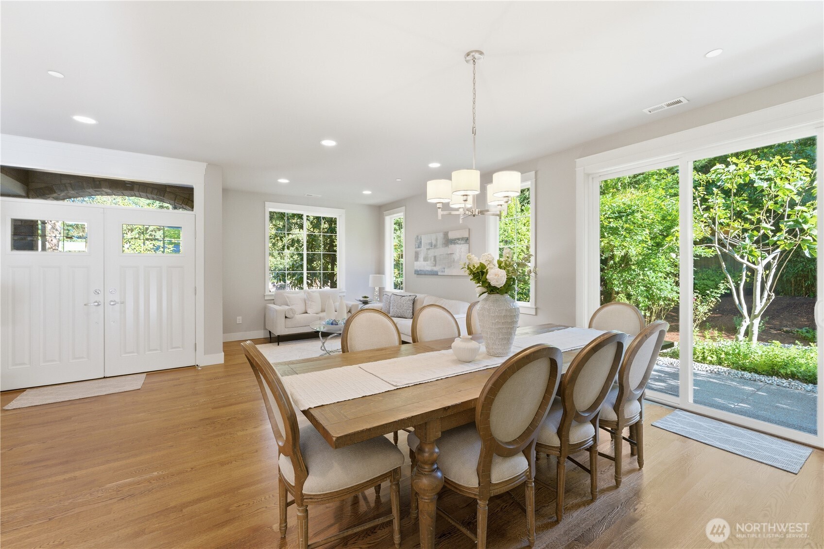 Just left of the front doors, the formal dining and living area enjoys a serene green outlook, with the patio beyond featuring fig, plum, and apple trees.