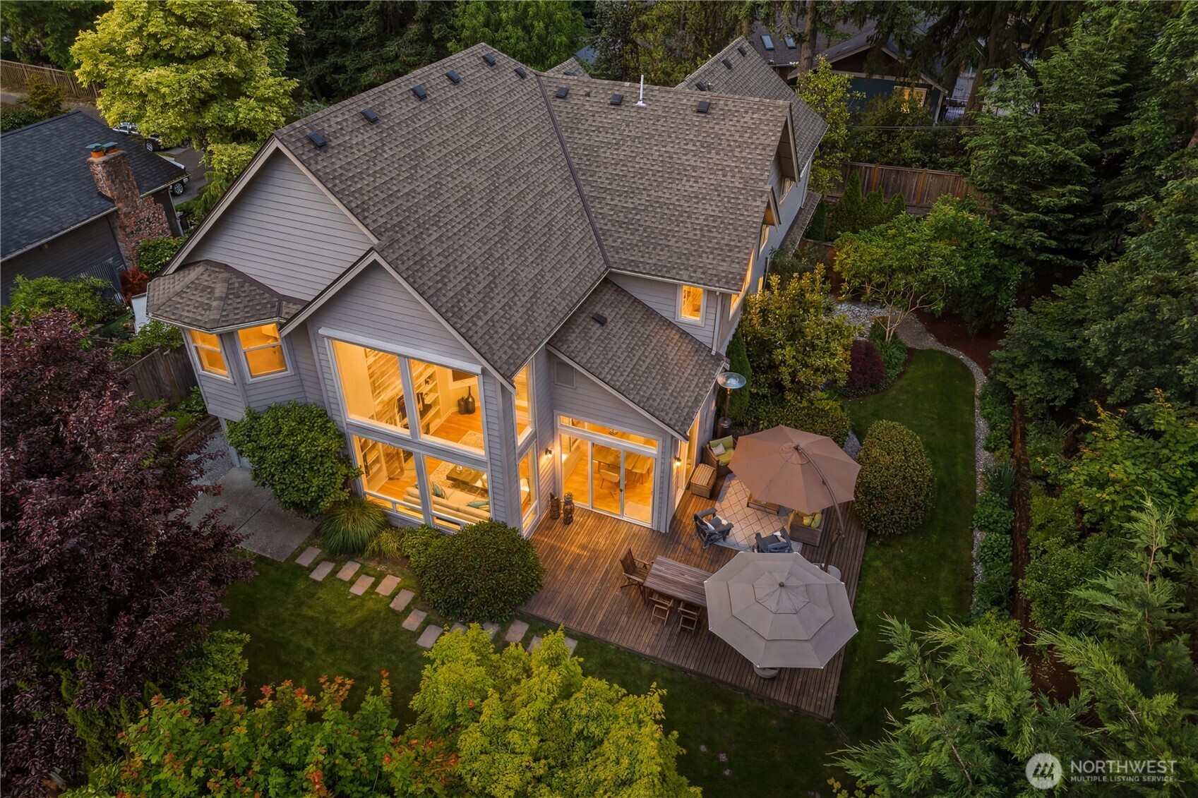 Twilight view of the home framed by lush, mature landscaping and an inviting cedar deck designed for year-round outdoor living