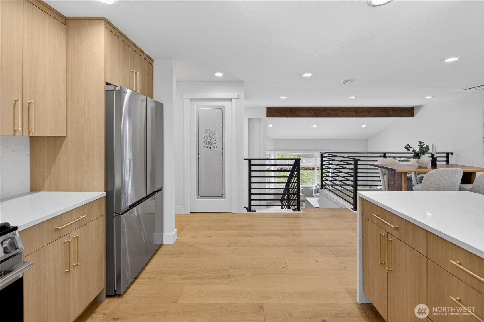 Brass-tone modern cabinet handles add a beautiful finishing touch, with clean lines that echo the custom linear railings for a cohesive designer look. The walk-in pantry, framed by a beautiful etched glass door, elevates the kitchen with both style and function, offering generous space for stored goods, small appliances, and all the baking essentials you like to keep close at hand.