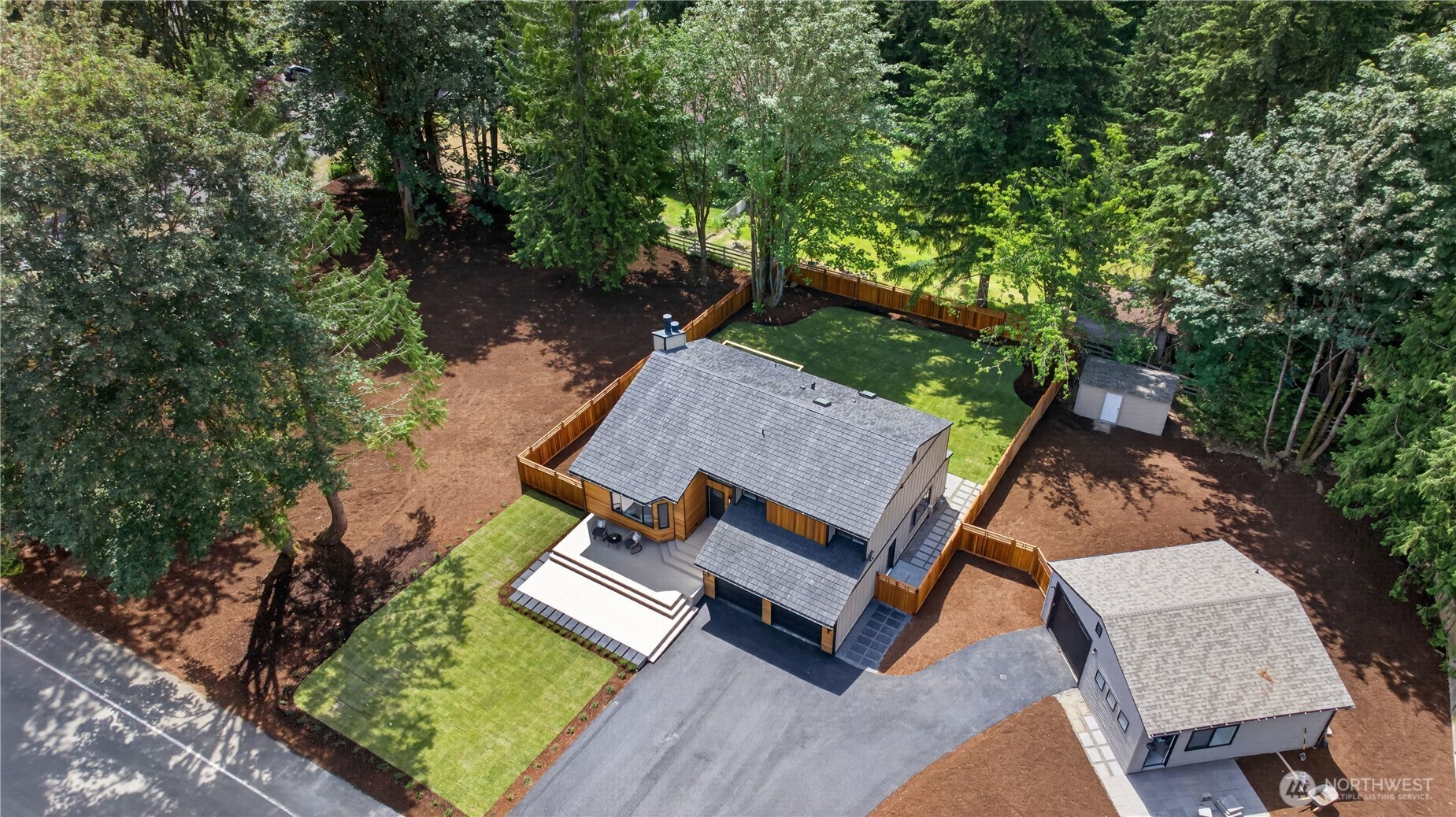 Beyond the deck, a large patio extends the outdoor living space and creates room for even more enjoyment of the back yard. It is easy to imagine lounge seating, play space, container gardens, or even a hot tub here, all alongside the flat lawn and lovely trees. Together, the deck, patio, and yard create a spacious setting for relaxing, entertaining, and everyday outdoor living.