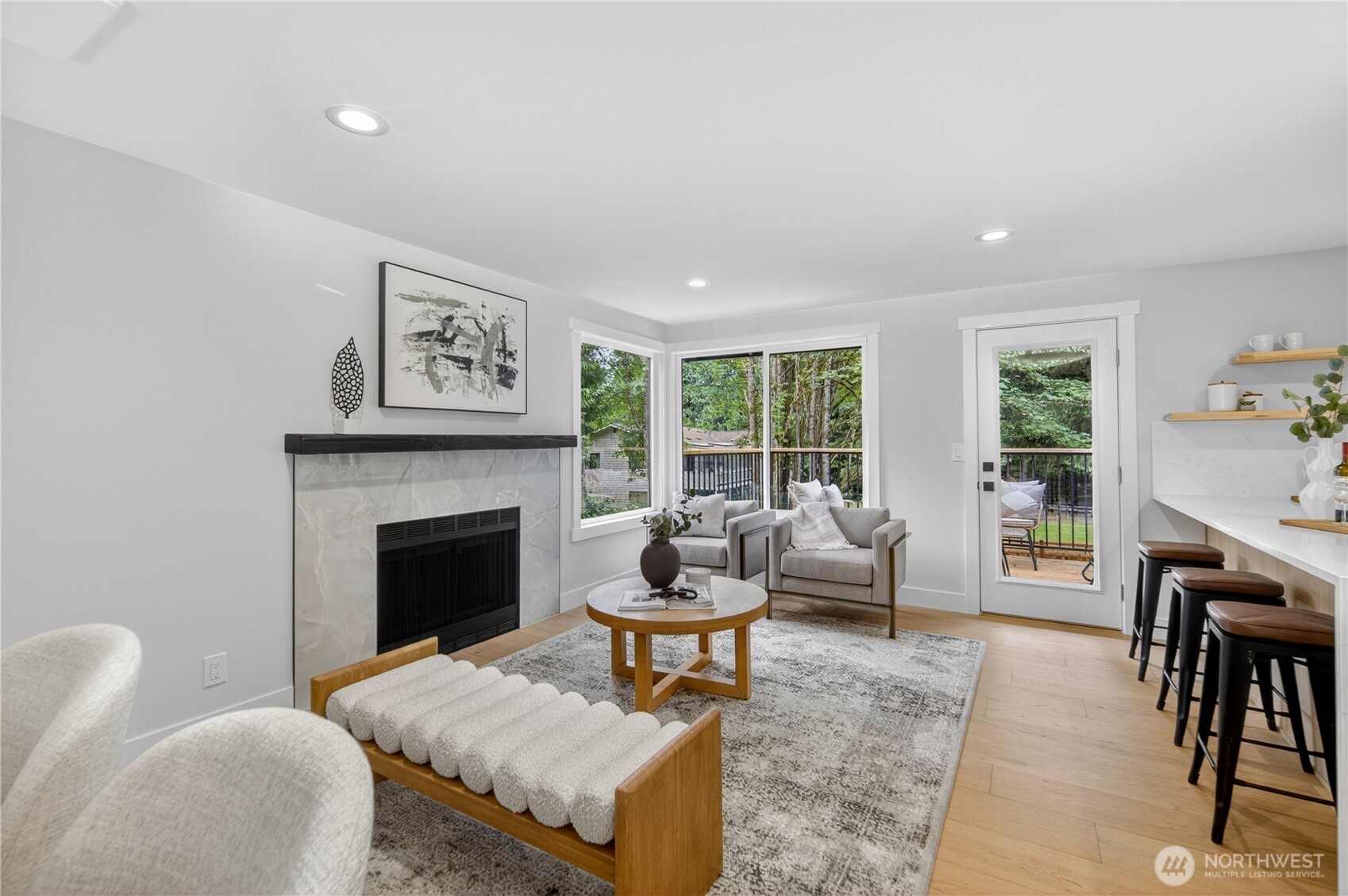 Large windows in the main living area draw in beautiful natural light all day and frame lovely views of the surrounding trees, while the door opens directly to the new expansive deck in the private back yard. The result is an easy, inviting connection between indoor living and the peaceful outdoor setting. As the day winds down, the southern exposure brings soft evening color into the room, with warm amber, lavender, and coral tones filtering through the trees.  All windows throughout the home are new double-pane storm windows, adding comfort and efficiency.