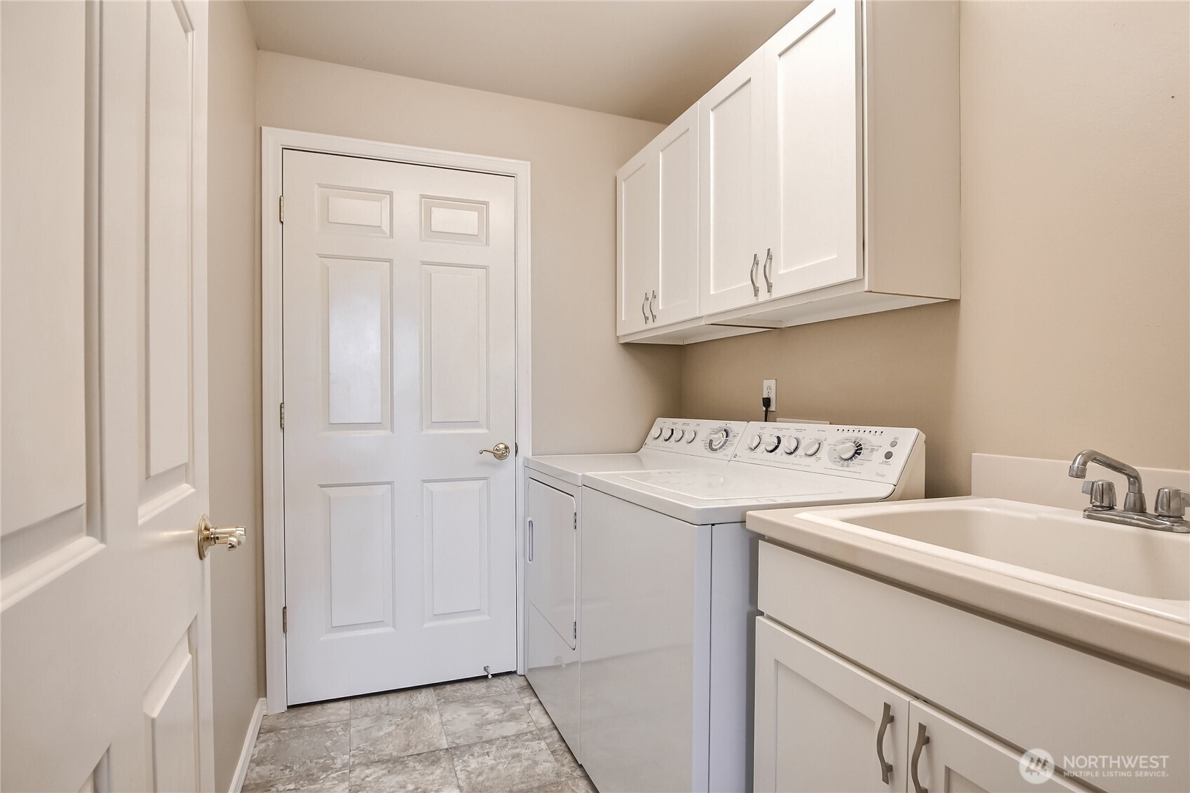 Laundry room with laundry sink, storage cabinets and closet.