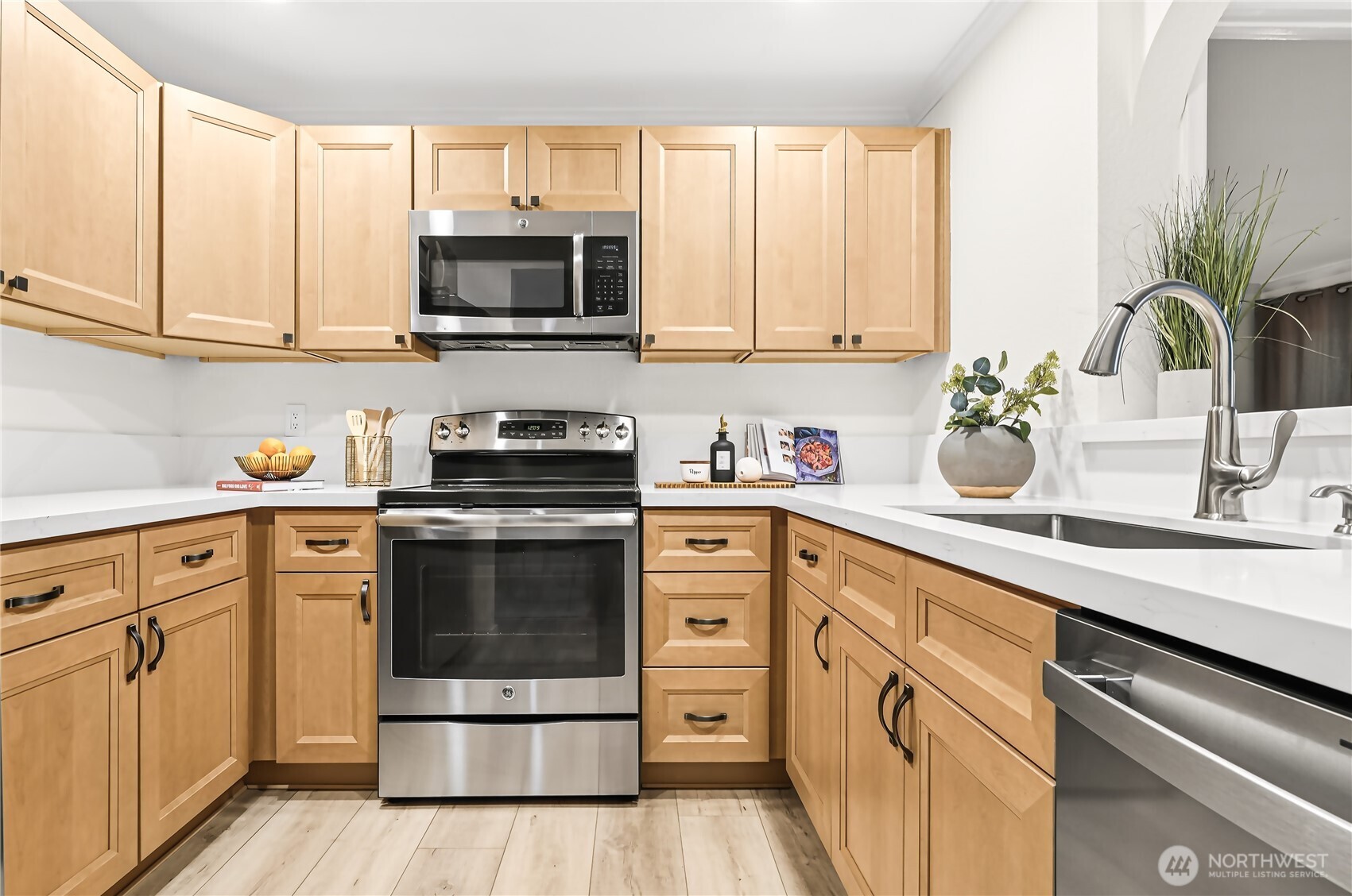 The kitchen has been completely refreshed with handsome new cabinetry, slab quartz countertops, and stainless-steel appliances, including a new refrigerator and dishwasher.