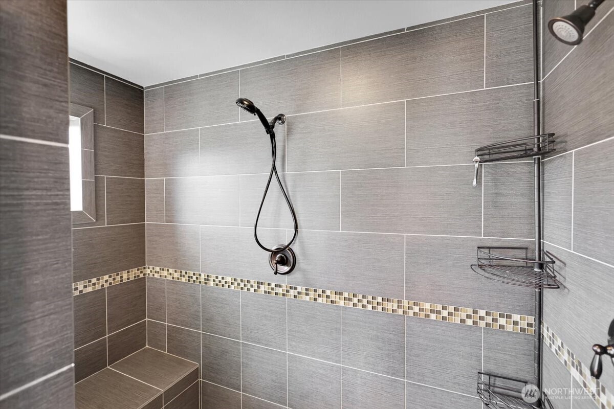 Primary Shower has Double Shower Heads and Sitting Bench