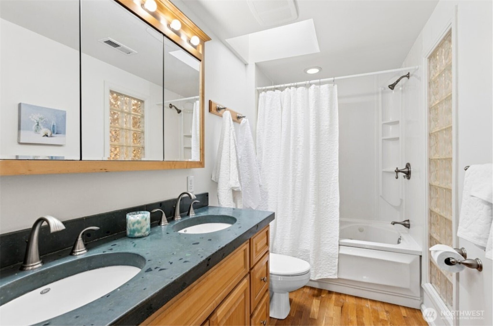 The adjoining primary bathroom with dual sinks and tub/shower and glass wall
