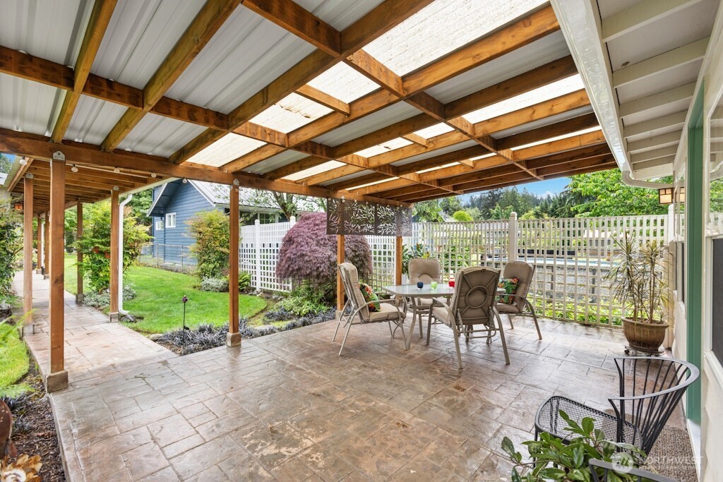 Covered patio area with stamped concrete overlooks the lush backyard with loads of fruit options!
