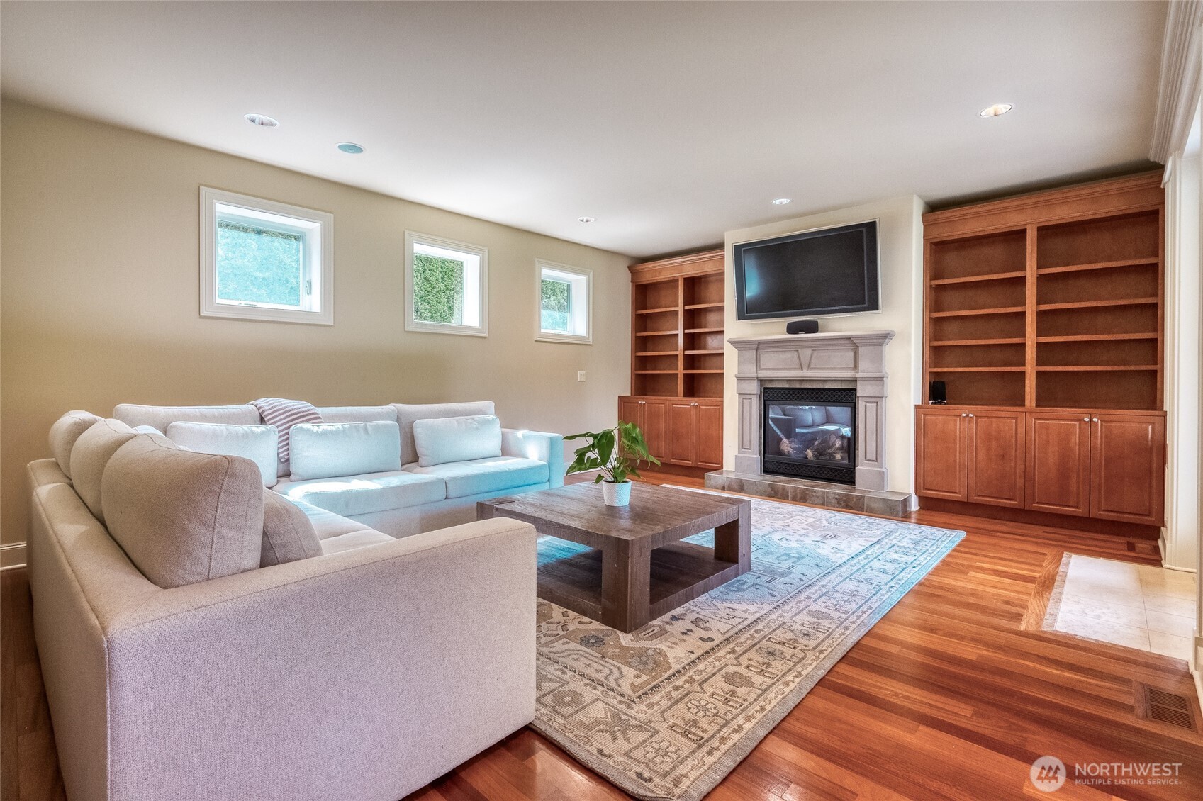 Spacious family room featuring a gas fireplace and elegant French doors opening to the patio garden, creating a seamless connection between indoor comfort and outdoor living. TV conveys with the sale.