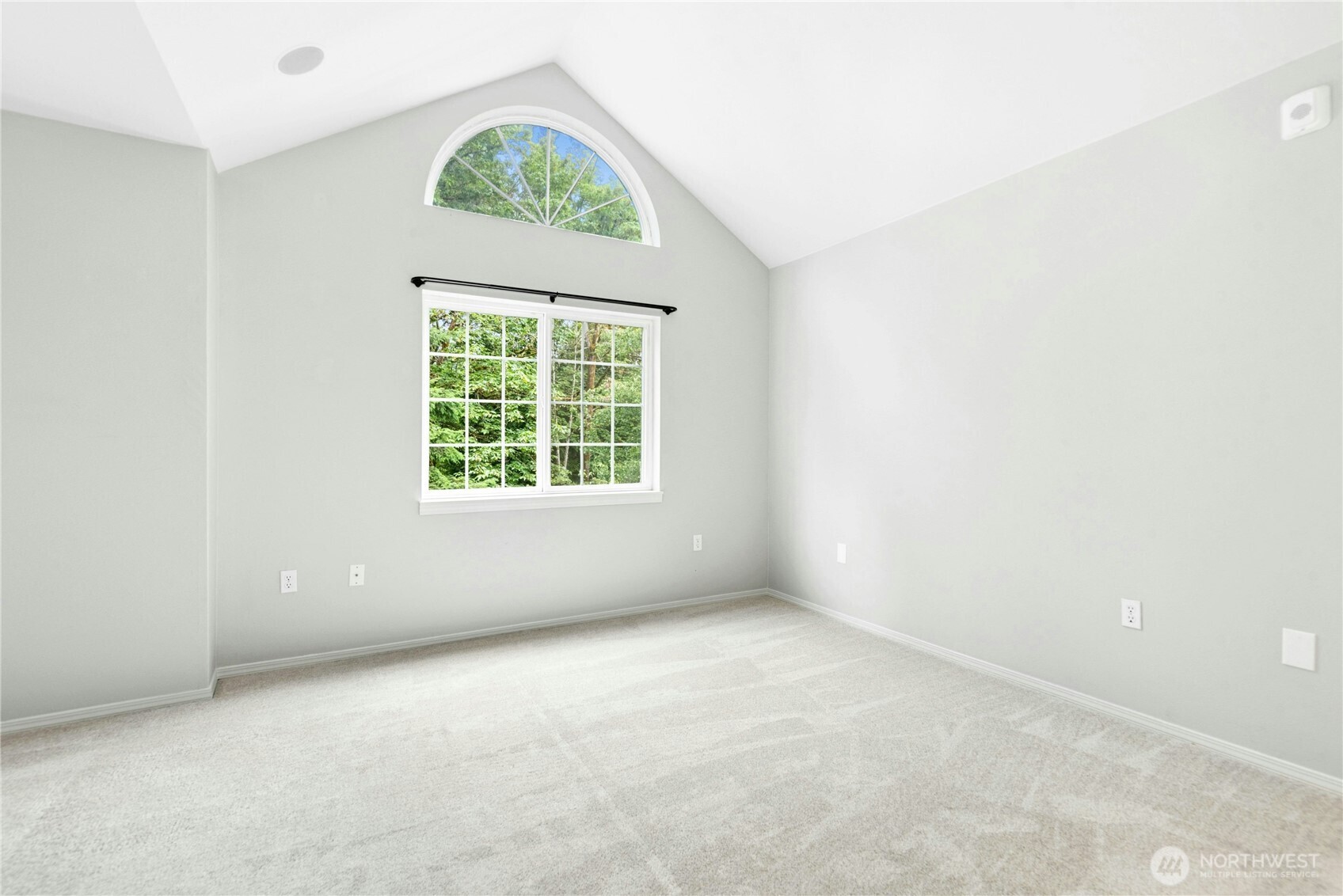 Primary bedroom featuring vaulted ceilings, an arched window, and abundant natural light.