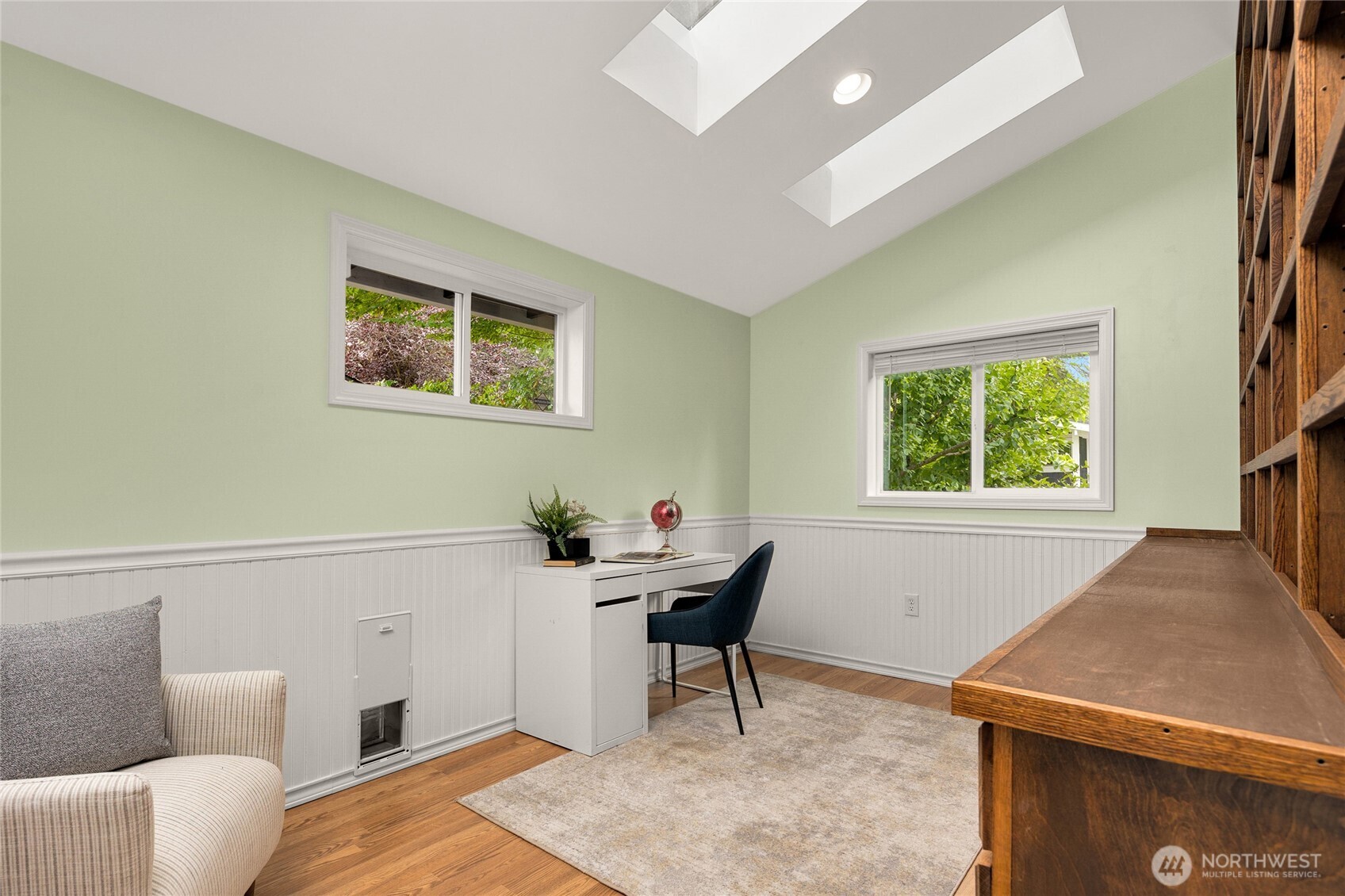 The lower level office or craft room with wainscoting, skylights & a view of the backyard. There is also a dog door that leads to an outside dog run.