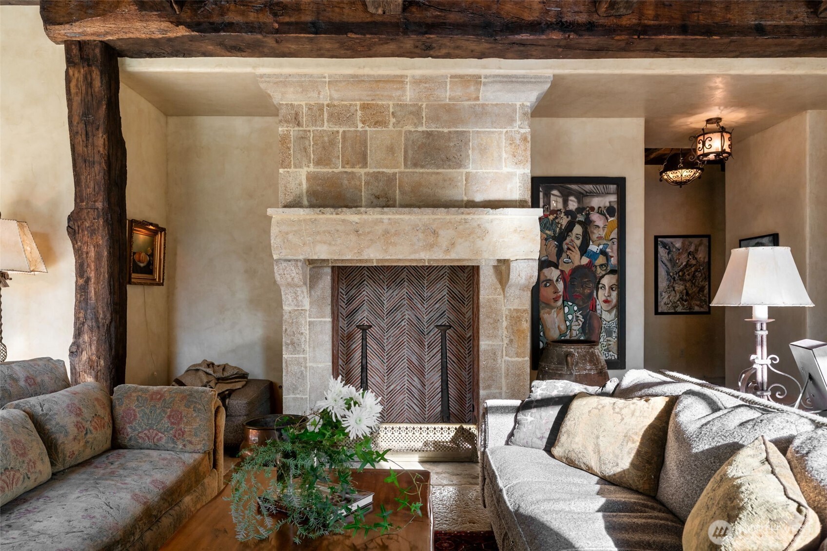 A refined gathering space where historic materials and modern comfort coexist seamlessly. A striking fireplace crafted from reclaimed French limestone anchors the room.