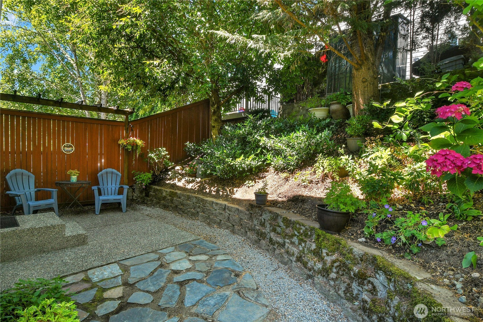 Aggregate and flagstone patio with Arboretum landscaping privacy fence, accented by a simple pergola-style crossbeam.