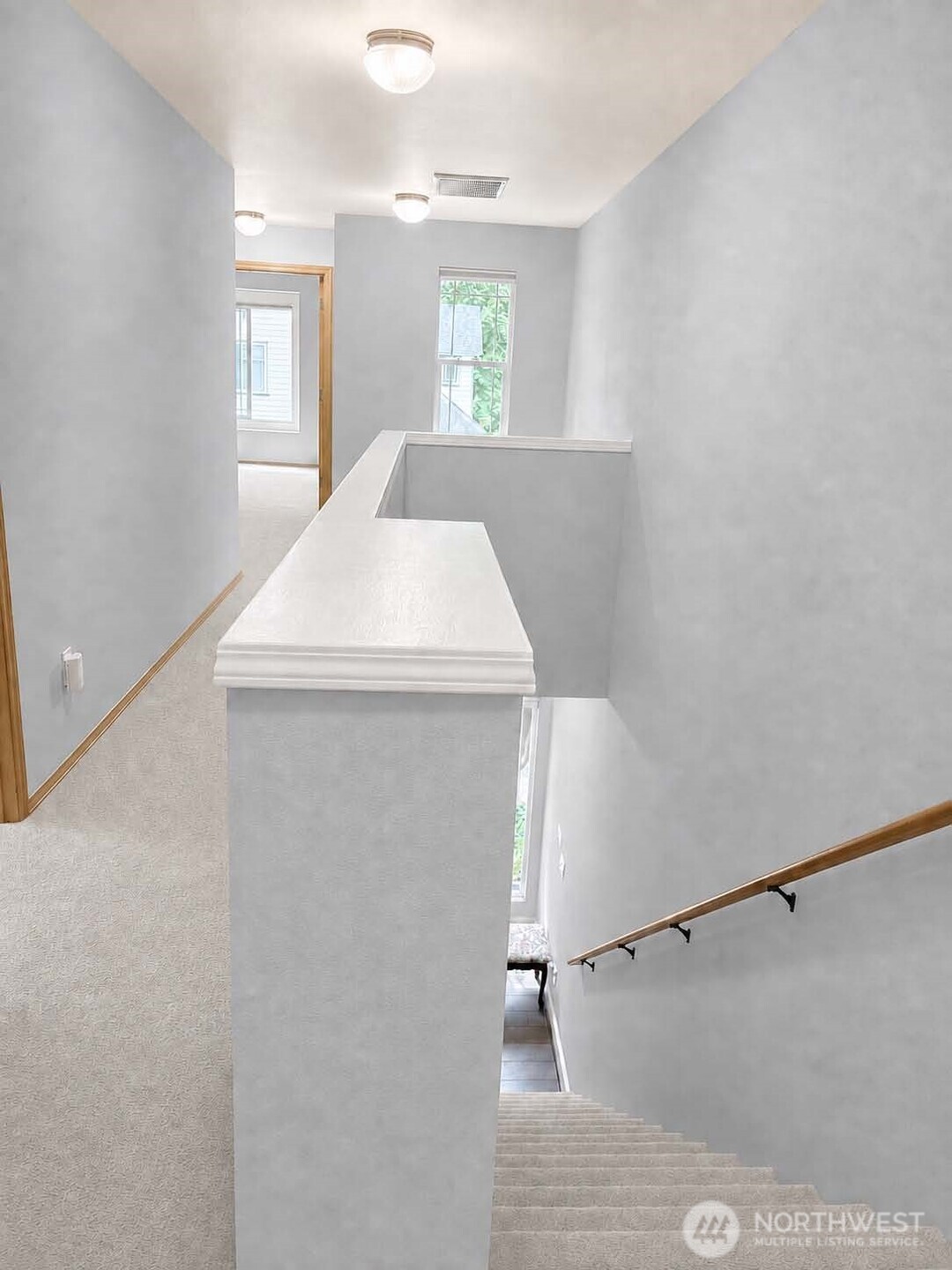 Open hallway with computer-workspace alcove. Neutral carpet. Hollywood-style carpeted stairs.