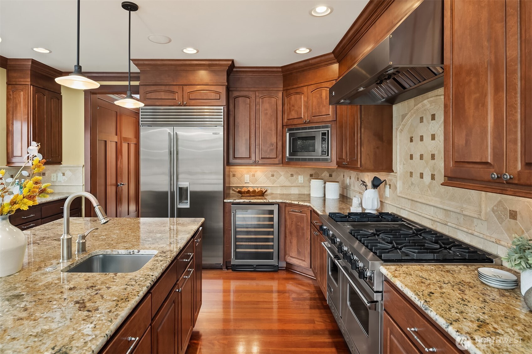 Designed for serious cooking and effortless hosting, the kitchen features professional-style appliances, expansive counters, a wine fridge, a large center island, and thoughtful storage throughout.