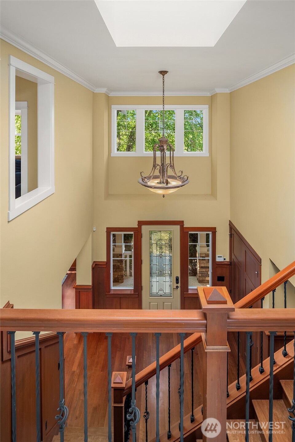 A dramatic two-story foyer welcomes guests with soaring ceilings, rich Craftsman millwork, warm hardwood floors, and abundant natural light.
