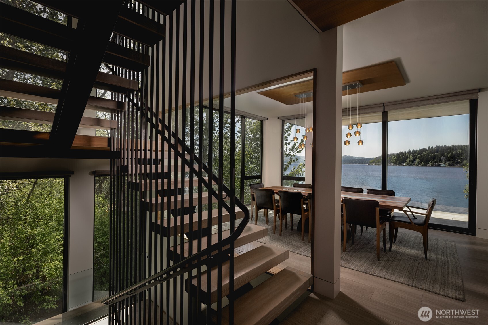 The architectural staircase moves upward through glass and trees, creating a sense of elevation as you move through the home.