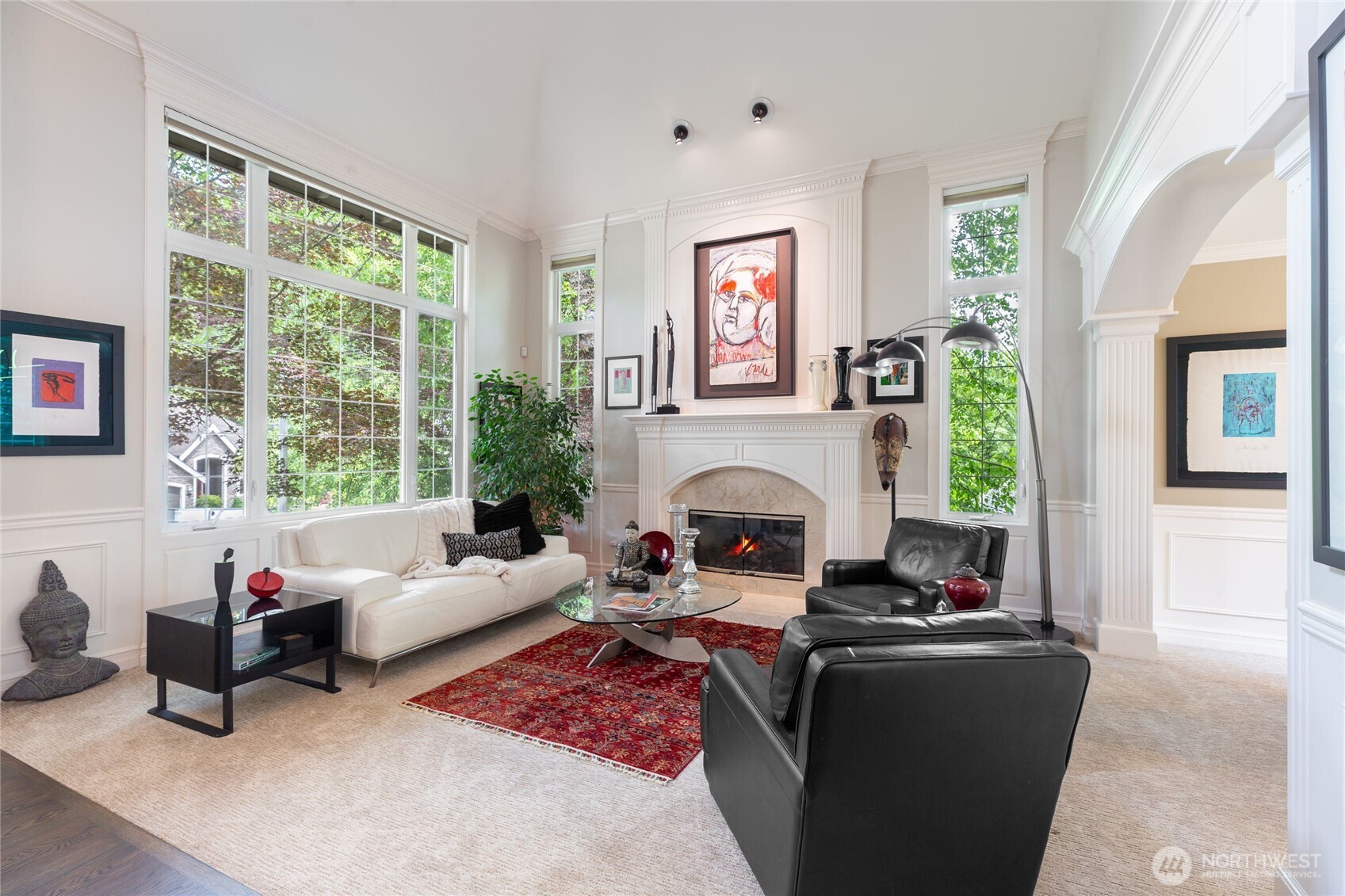 “Light-filled living room with expansive windows overlooking Cougar Mountain, creating a warm, inviting space anchored by a classic fireplace.