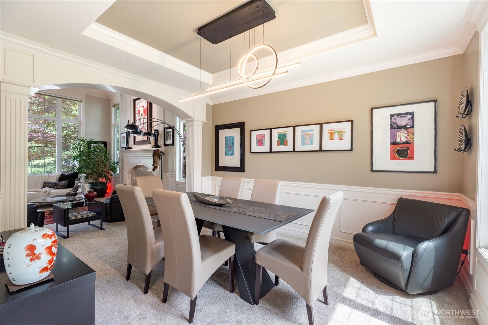 Formal dining room with tray ceiling and modern statement lighting.