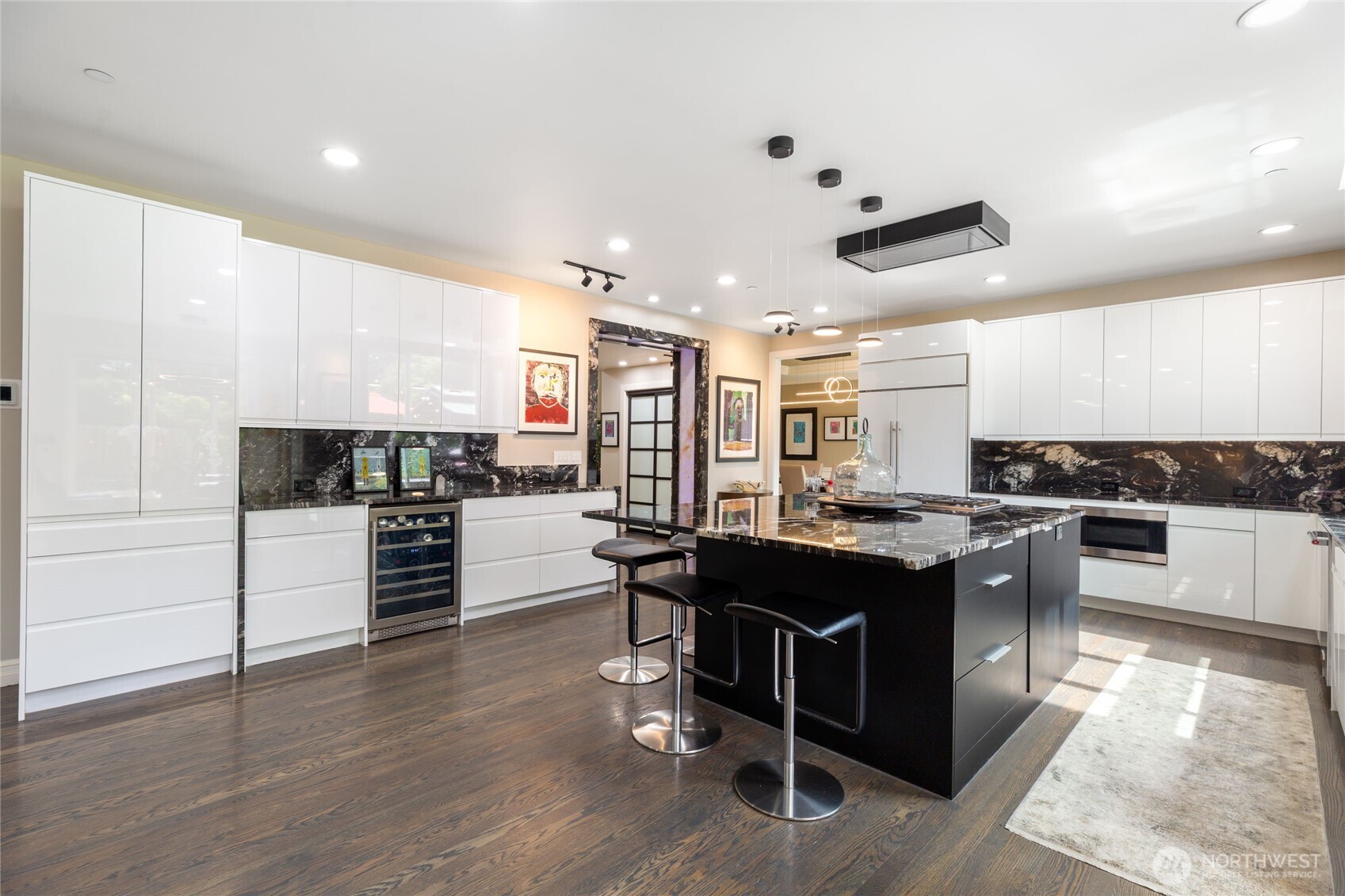 Expansive kitchen with modern custom cabinetry, integrated wine storage, Wolf and Sub-Zero appliances, striking stone backsplash, and designer lighting—blending style and functionality throughout