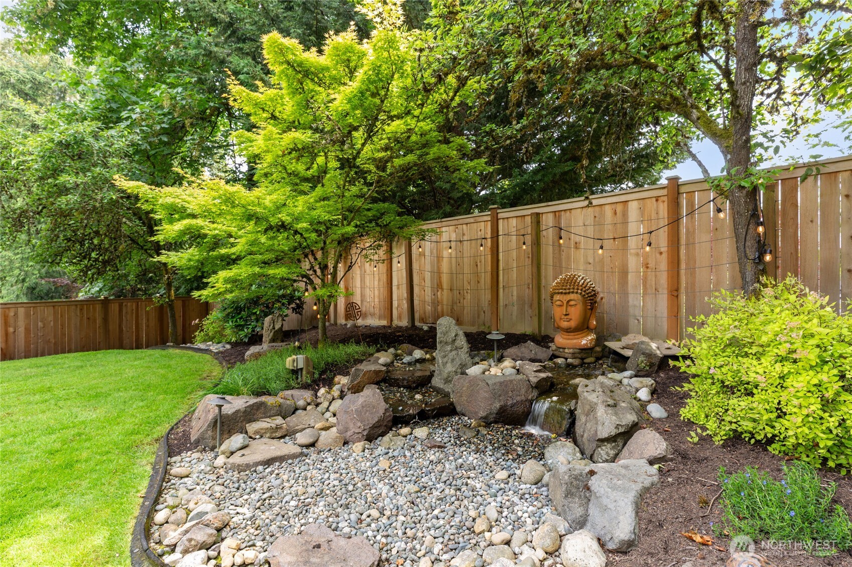 Resort-style backyard oasis featuring an expansive stone patio,  outdoor bar, and dining area with café lighting—perfect for entertaining.