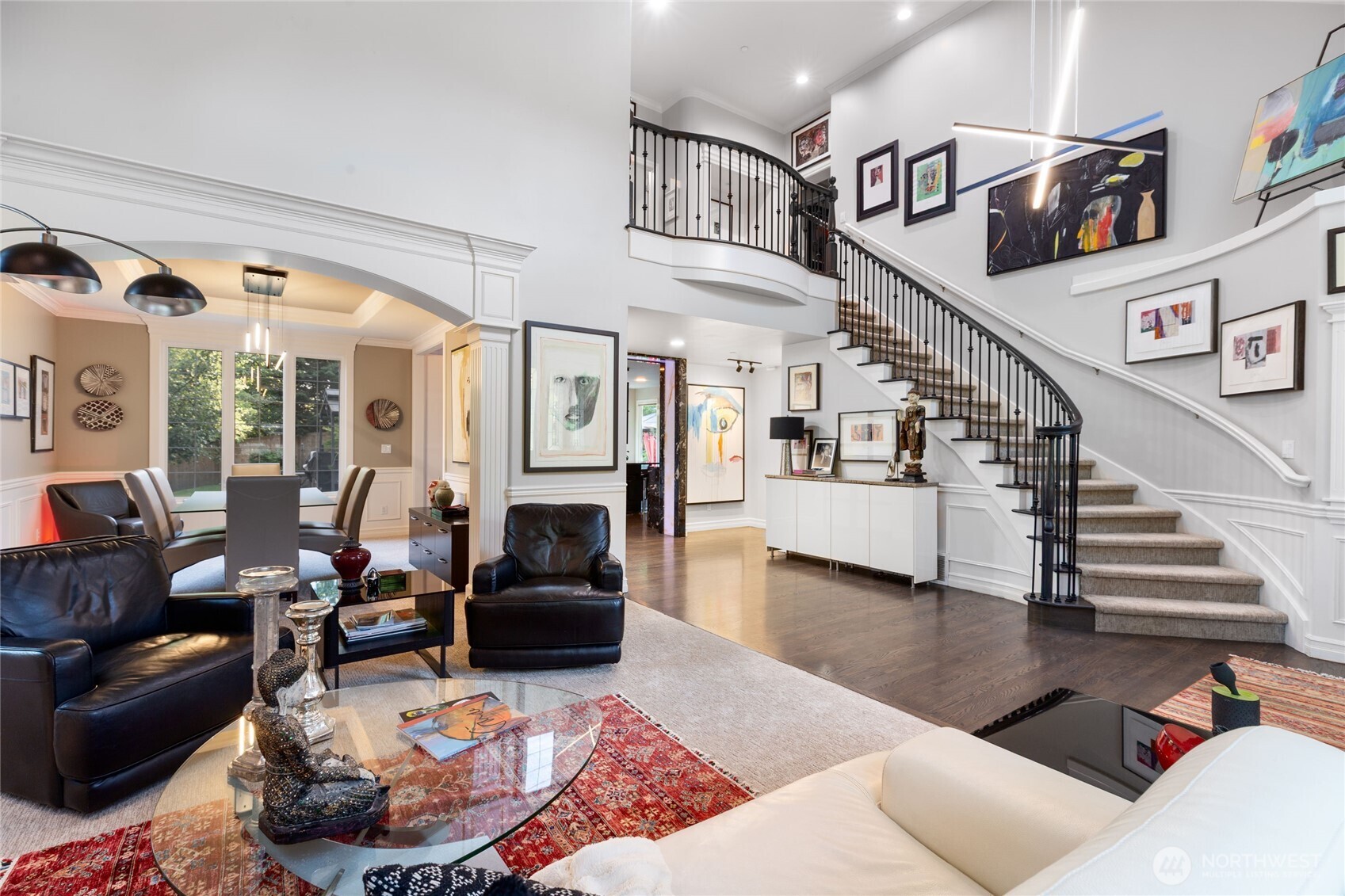 Dramatic curved staircase with wrought-iron railing anchors the main living area, complemented by soaring ceilings and seamless flow into the dining space—ideal for both everyday living and entertaining.