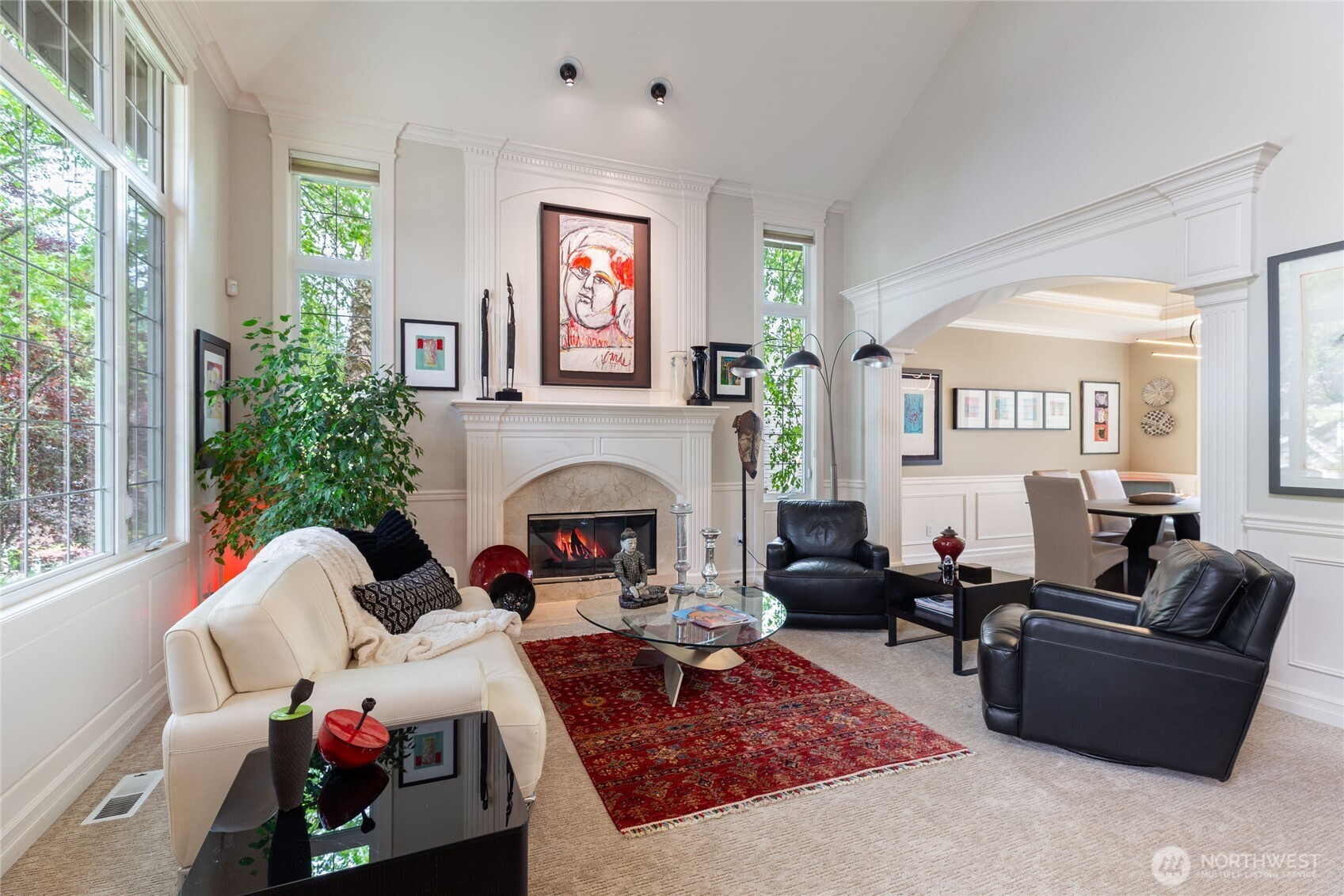 Elegant living room with soaring ceilings, a statement fireplace, and seamless flow into the dining area—designed for both everyday living and effortless entertaining
