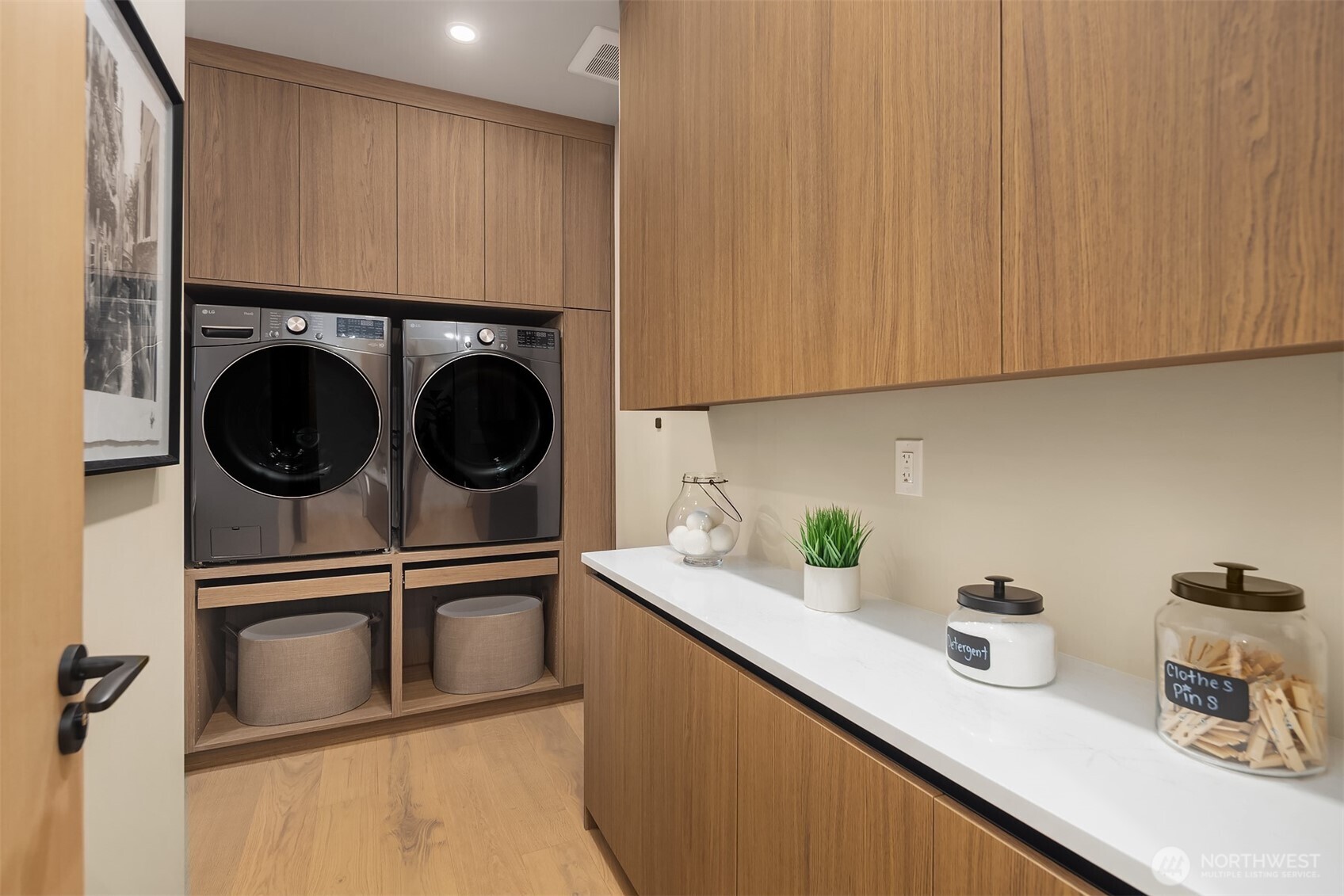 Laundry with raised machine & basket drawers + sink around corner & storage