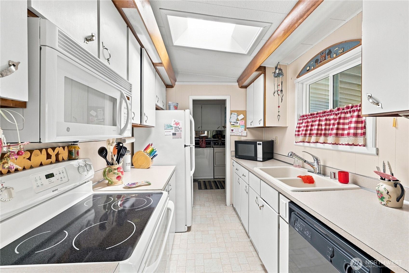 This view of the kitchen shows the utility room.  This angle distorts the range/oven & dishwasher. They aren't as wide as this photo depicts.