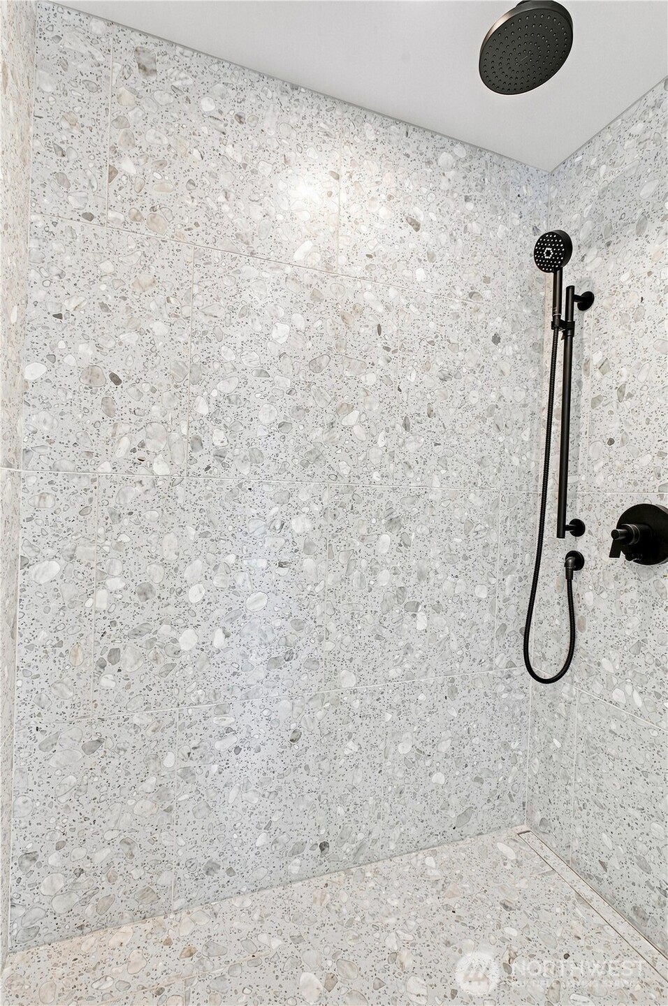 A luxurious ensuite primary bath wrapped in Italian marble from floor to ceiling, with rich dark wood cabinetry, a sculptural soaking tub, and a generous walk-in shower—an elegant private retreat designed for quiet indulgence.