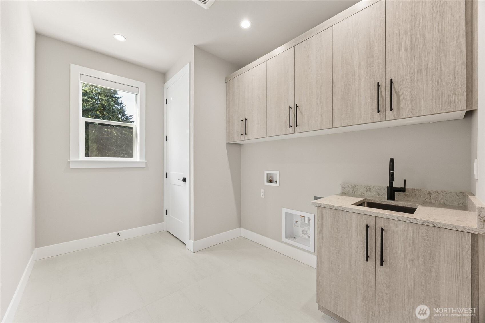 Convenient upstairs laundry room with built in cabinetry, utility sink, and ample storage.