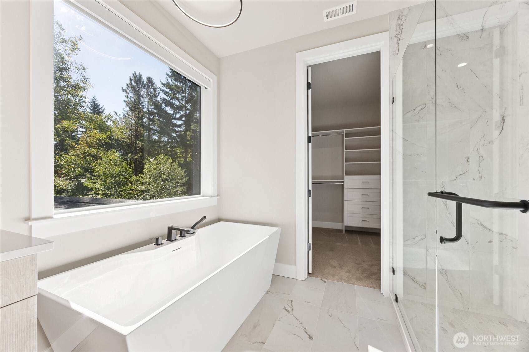 Spa inspired primary bathroom features a freestanding soaking tub, walk in shower, and spacious walk in closet.