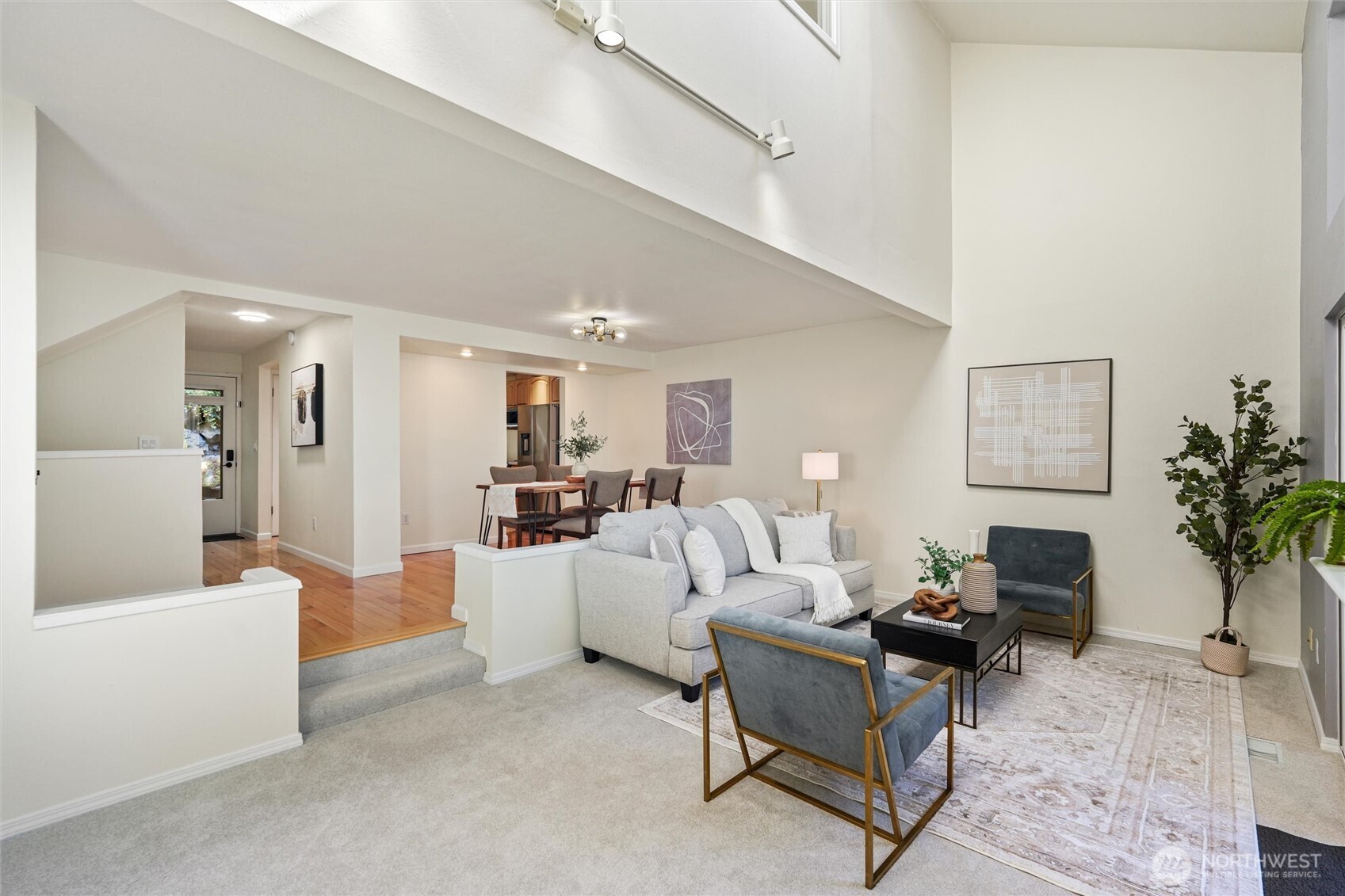 A bright and spacious living room with vaulted, tall ceilings and a wall of windows that brings in exceptional natural light