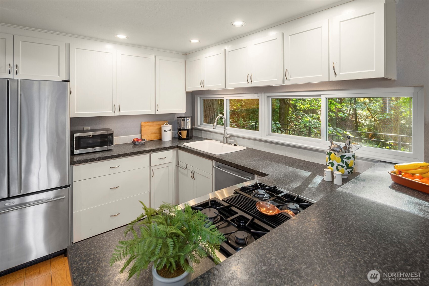 Efficient kitchen with stainless steel appliances and white shaker cabinets, plus updated lighting