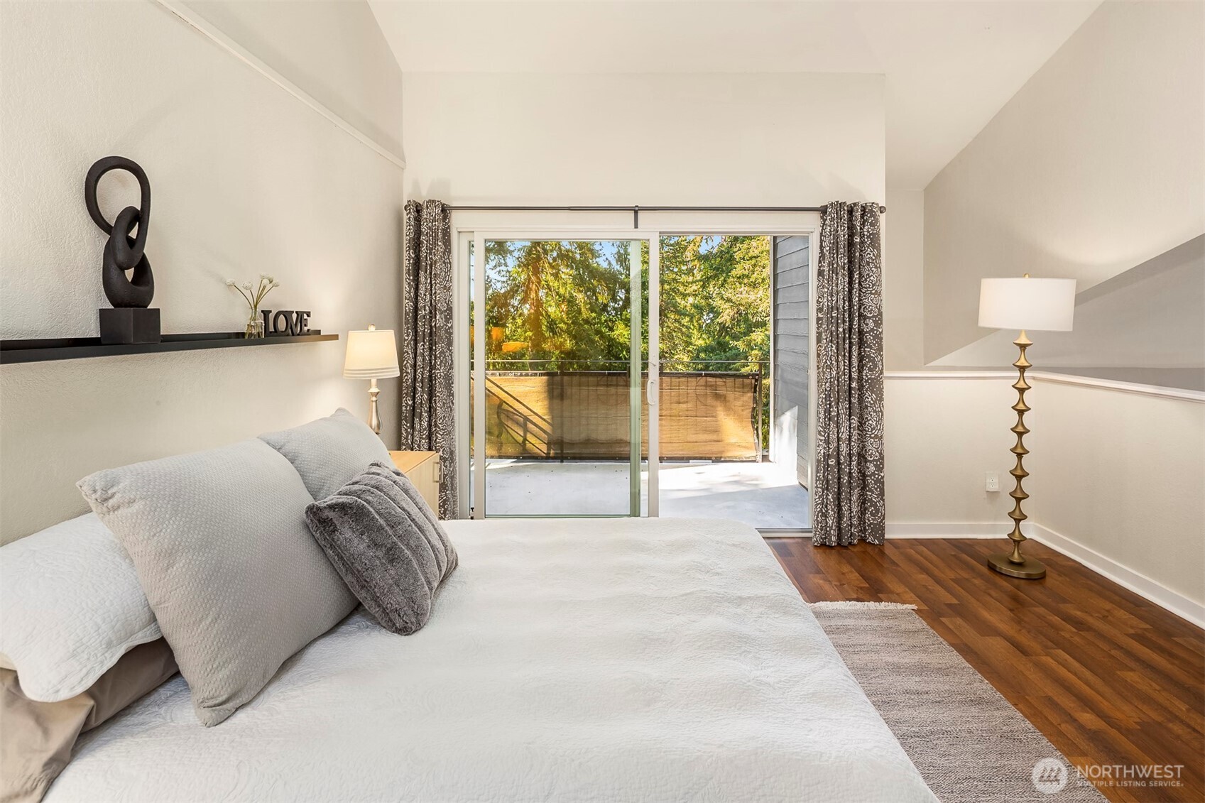 Primary suite with solid wood planked hardwoods and vaulted ceiling