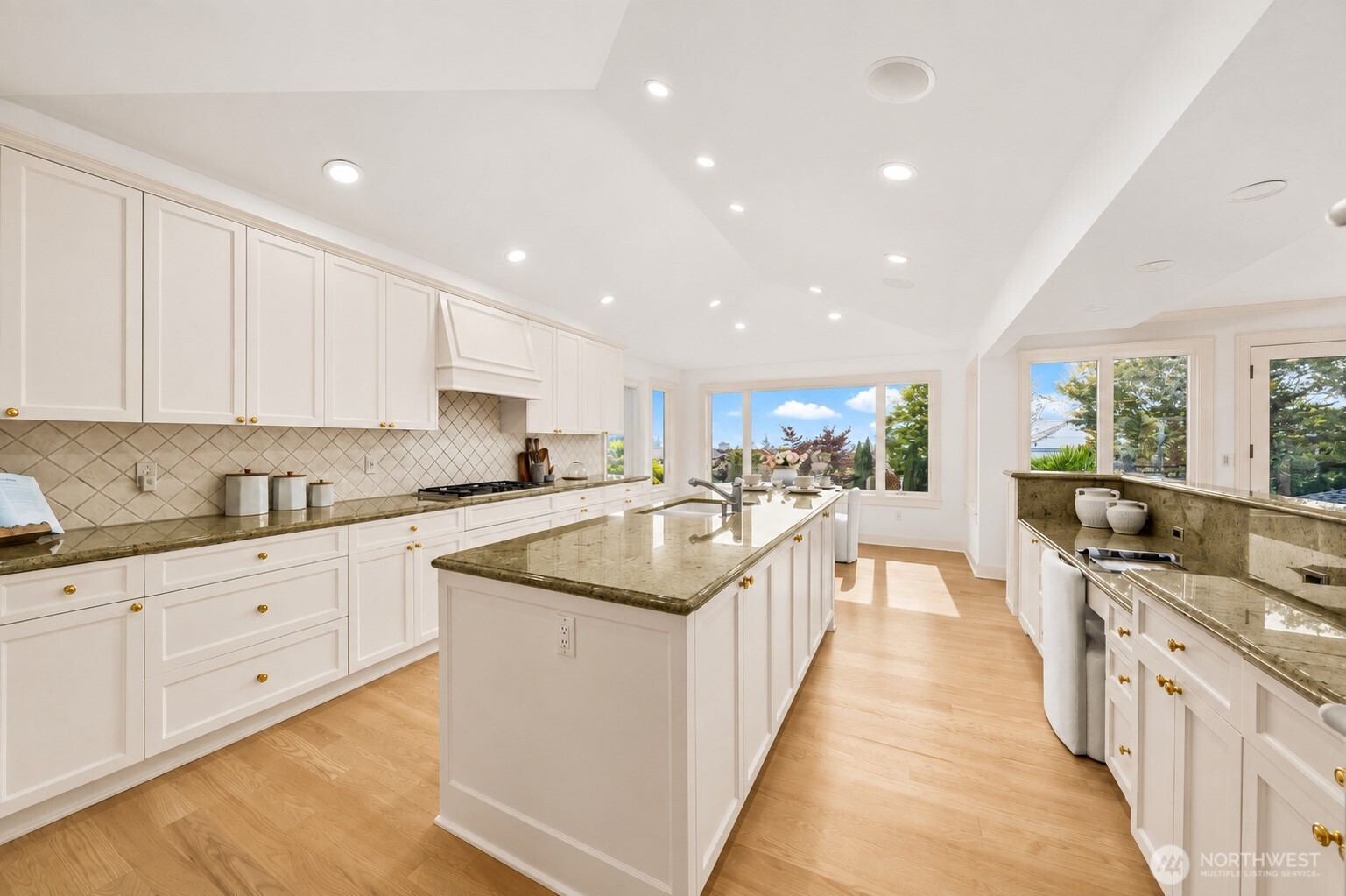 An expansive, light-filled kitchen featuring abundant cabinetry, generous counter space, a large center island, t and seamlessly connect to the breakfast nook and garden views.