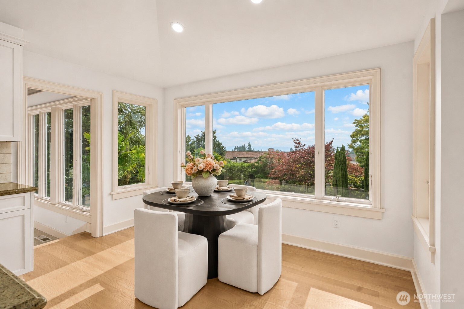 A bright and inviting breakfast area framed by expansive windows, offering beautiful garden and territorial views.