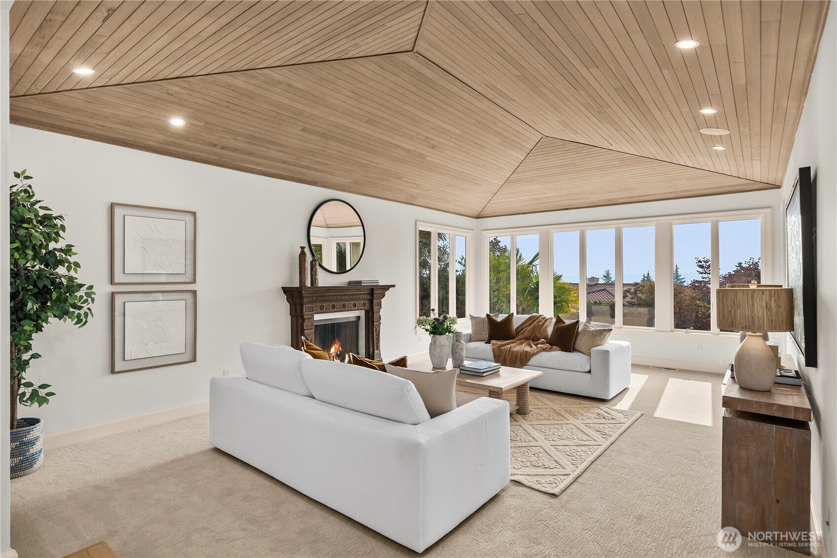 Expansive windows frame beautiful garden views, while the richly detailed fireplace creates an inviting focal point