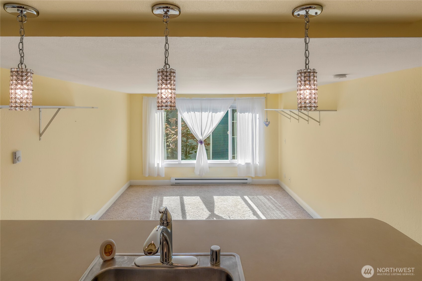 Kitchen breakfast bar with crystal pendant lighting and southwest-facing window beyond.