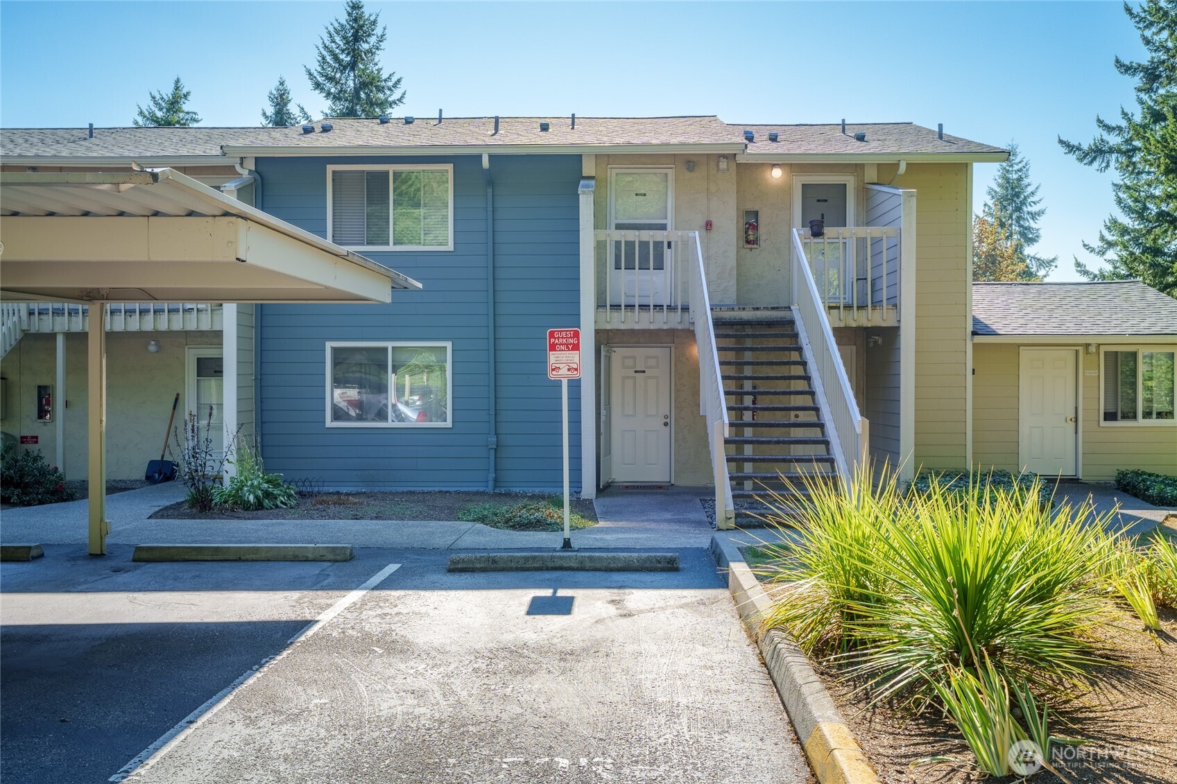 Unit entrance with guest parking nearby; community laundry room entrance visible at right.