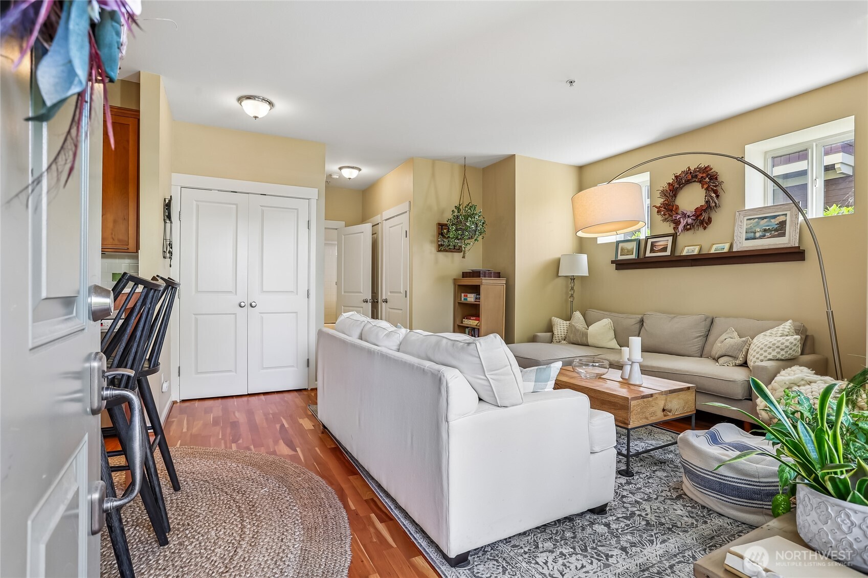 Bright and inviting living room featuring beautiful engineered hardwood floors, soaring 9-foot ceilings, and an open-concept layout. Large windows bring in plenty of natural light, creating a warm and welcoming space for relaxing or entertaining. The living area flows seamlessly into the kitchen, maximizing the condo’s efficient floor plan.
