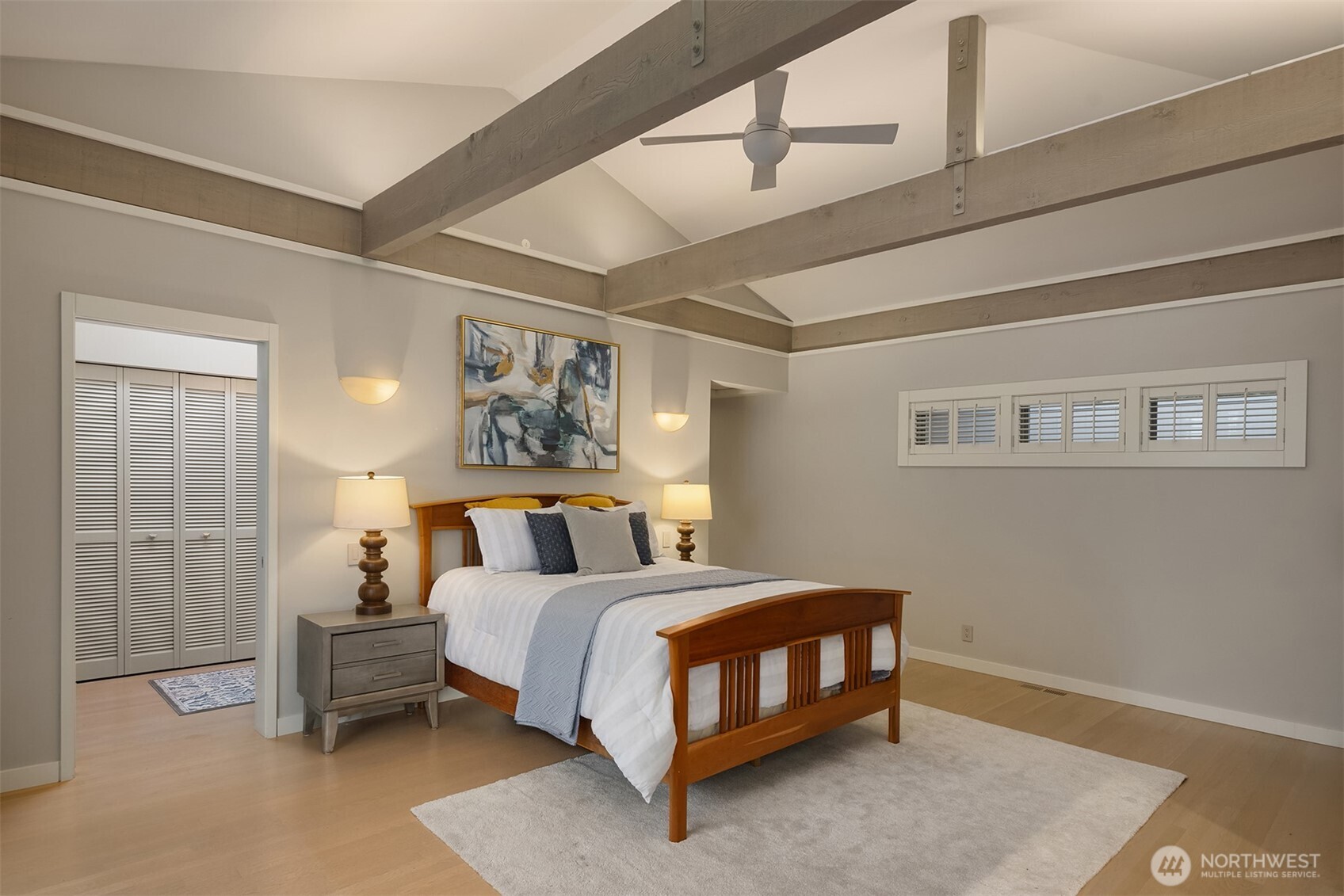 Spacious guest or primary bedroom on the main level with en suite three-quarter bathroom and a private lake view deck.