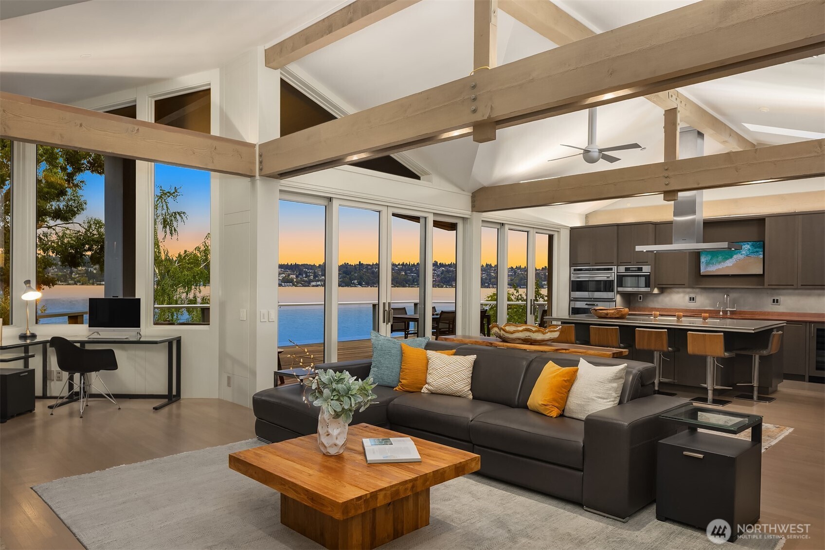 Open kitchen and family room with wood beaming detailing and walls of glass windows and doors opening to the expansive entertaining deck.